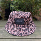 The VERSACE E72GAZK08-EZG089-EY4V bucket hat rests on a wooden surface, surrounded by lush greenery.