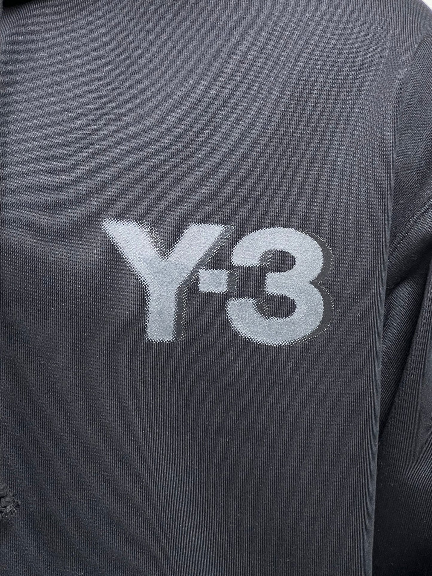 Close-up of a dark French terry fabric featuring the Y-3 logo printed in light gray, embodying the signature style of the ADIDAS x Y-3 JE9278 Logo Zip Hoodie Black.