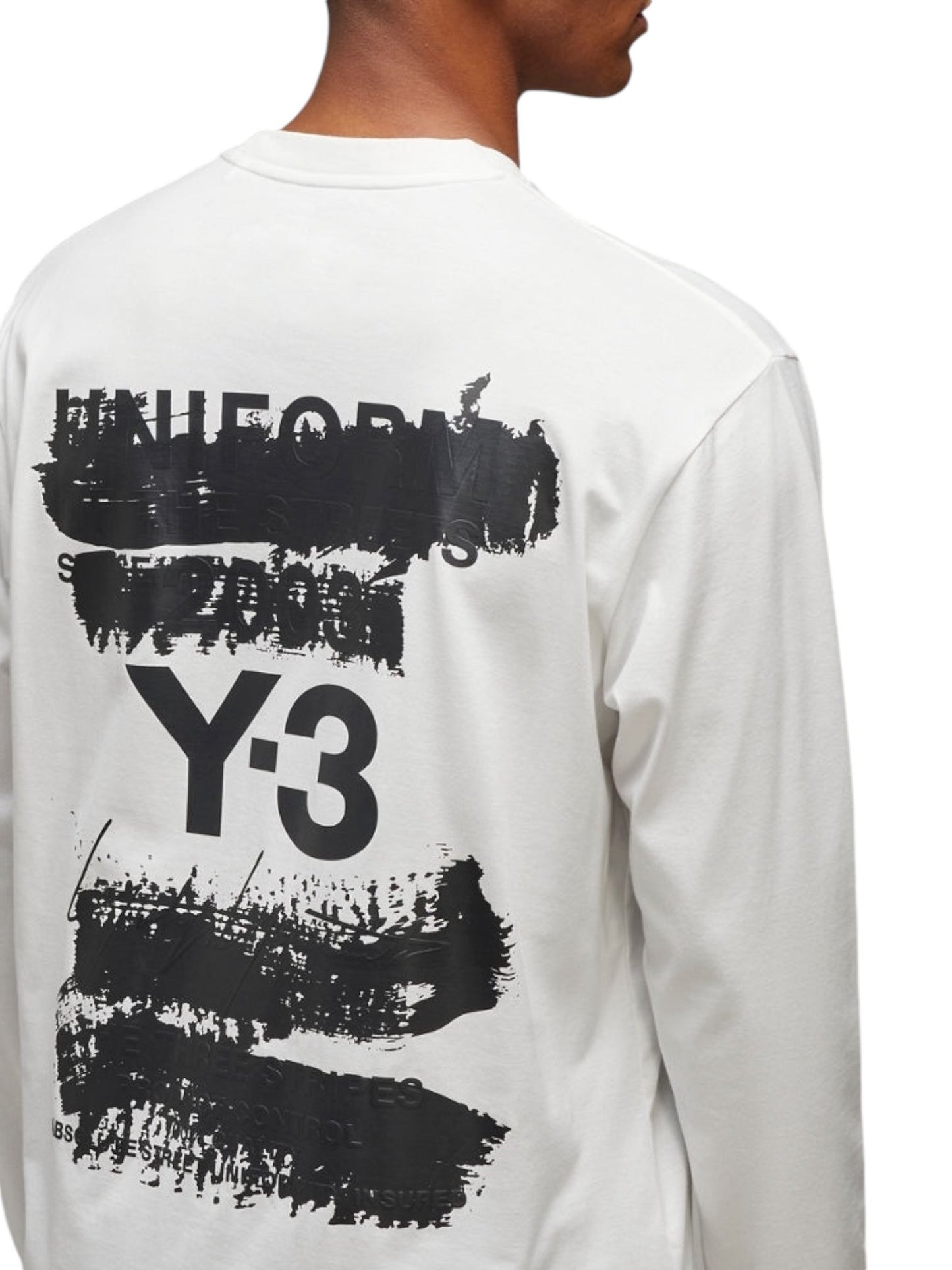 Back view of a person wearing the Y-3 JM3234 U GFX LS Tee Cwhite by ADIDAS x Y-3, featuring a white long-sleeve cotton fabric with black abstract text and graphic design, including "Y-3", on the back.