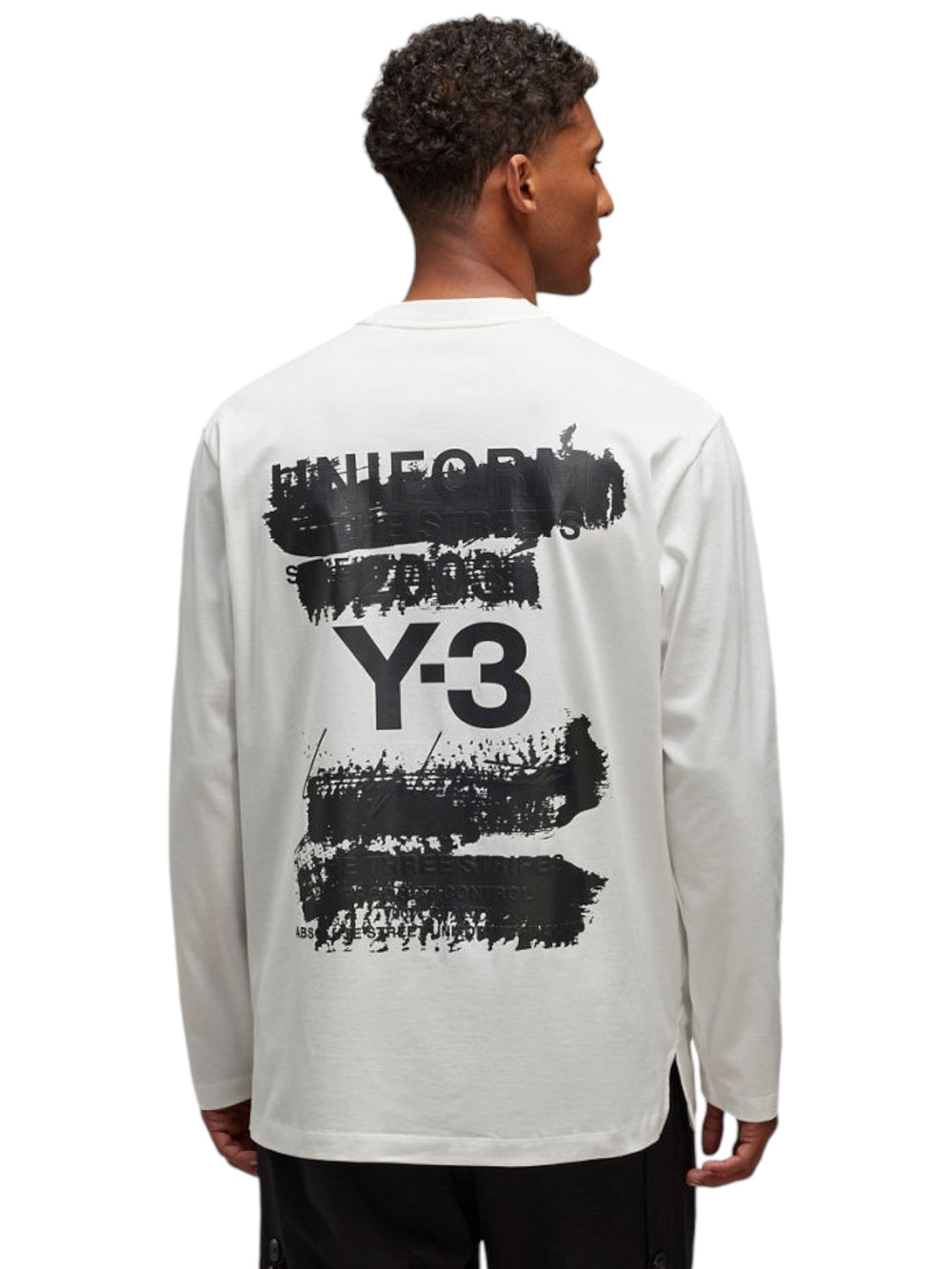 A person wearing the Y-3 JM3234 U GFX LS Tee Cwhite, a collaboration from ADIDAS x Y-3, showcases bold black graphic text and iconic designs on the back in white cotton fabric.