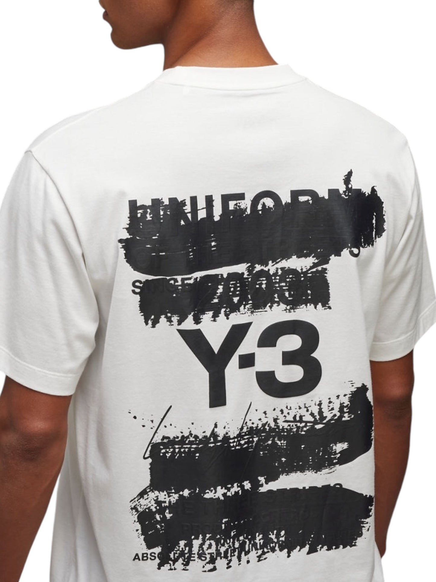 A man wearing the Y-3 JM7815 U GFX SS Tee Cwhite from ADIDAS x Y-3 showcases the distinctive black paint-like strokes and "Y-3" text on its soft cotton fabric.