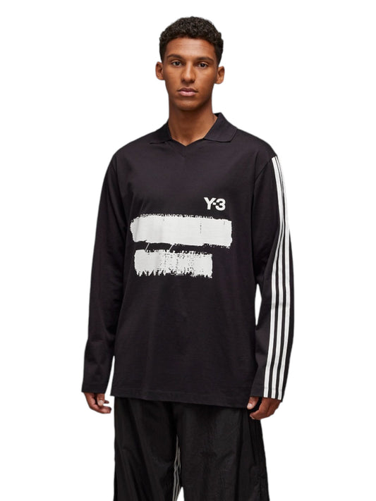 Individual dressed in the Y-3 JN4876 U GFX Logo LS T Black by ADIDAS x Y-3, showcasing a captivating white logo design and striped sleeve accents on luxurious cotton material. Photographed against a white backdrop.