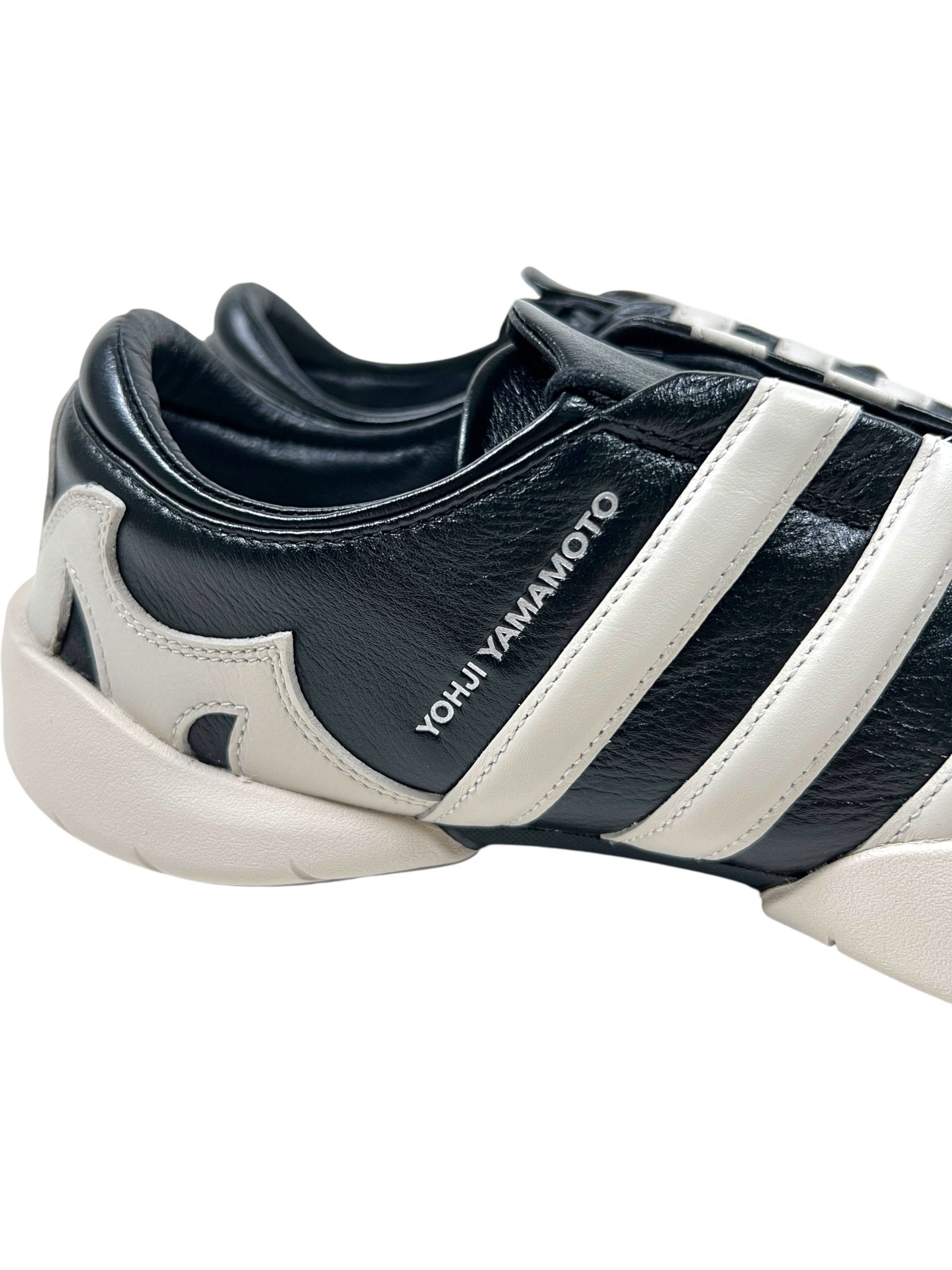 Close-up of the ADIDAS x Y-3 JR3600 Regu 2002 Black/Alumin sneaker featuring black and white leather, white stripes, a Torsion plate, and "Yohji Yamamoto" text on the side.