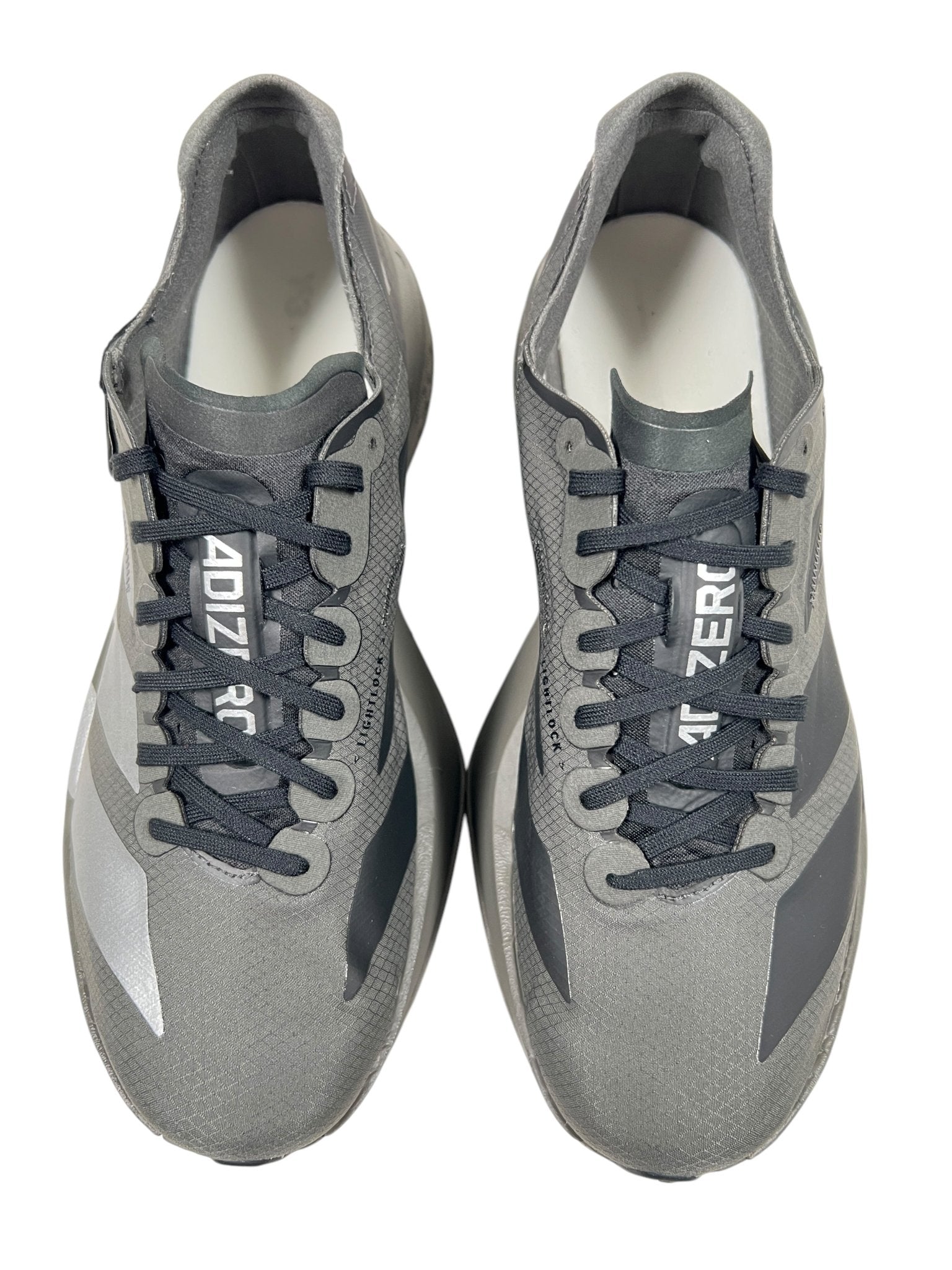 A pair of Y-3 JS3155 Y-3 Adios Pro 4 M sneakers in Cinder/Black by ADIDAS x Y-3, showcasing black laces and the iconic 3-Stripes, with "ADIZERO" elegantly printed on the tongue, viewed from above.