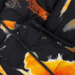 Close-up of the ADIDAS x Y-3 KA2364 M AOP Puff JKT in Multco/Black, featuring a black polyamide base with an abstract orange, yellow, and white tie-dye pattern and a visible zipper.