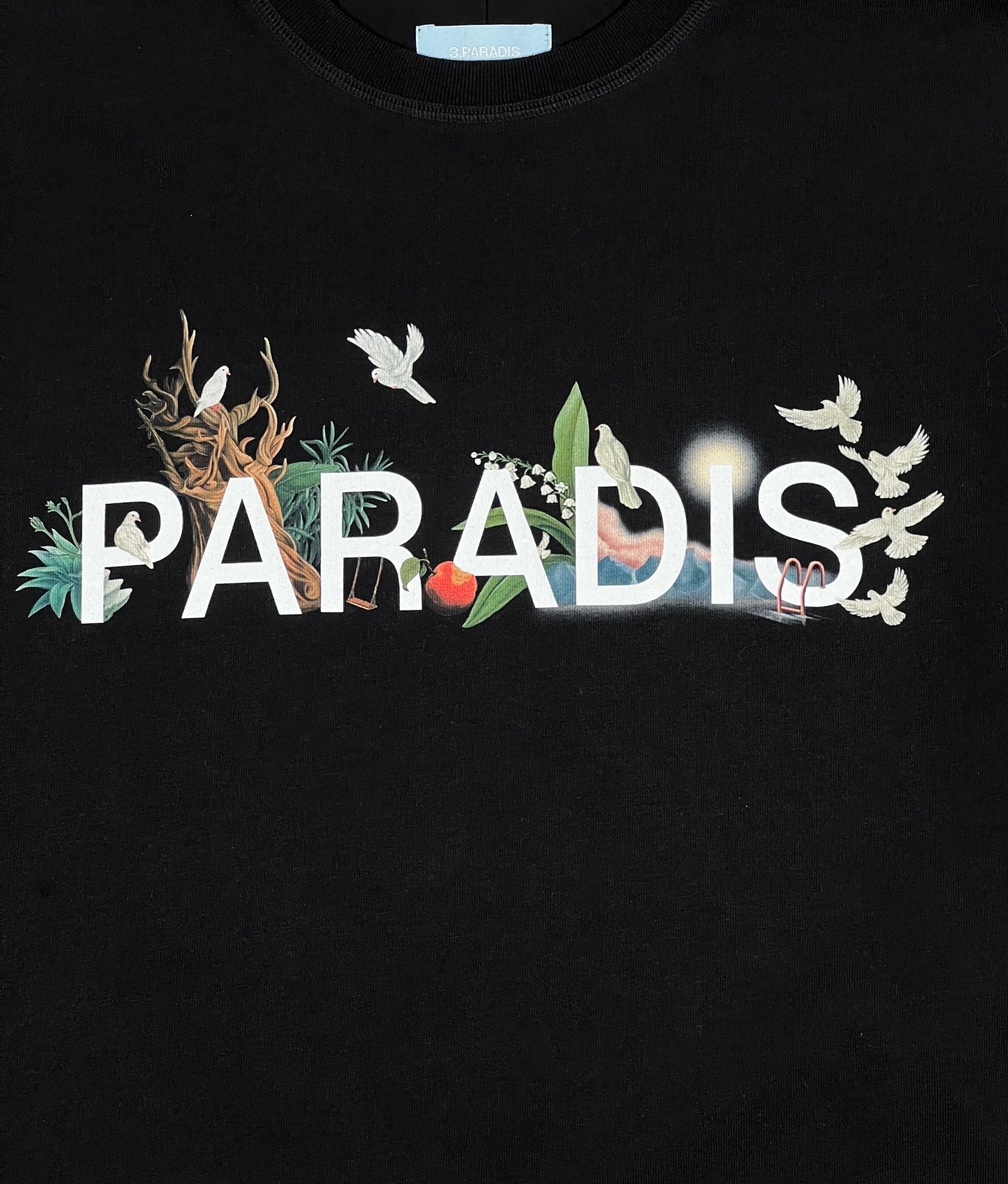 The image showcases the 3.Paradis SS T-Shirt Paradis Blk, a trendy graphic tee from 3.PARADIS featuring "PARADIS" printed in white on a black background. It's adorned with birds, leaves, and other nature elements and is made from 100% cotton for exceptional comfort.