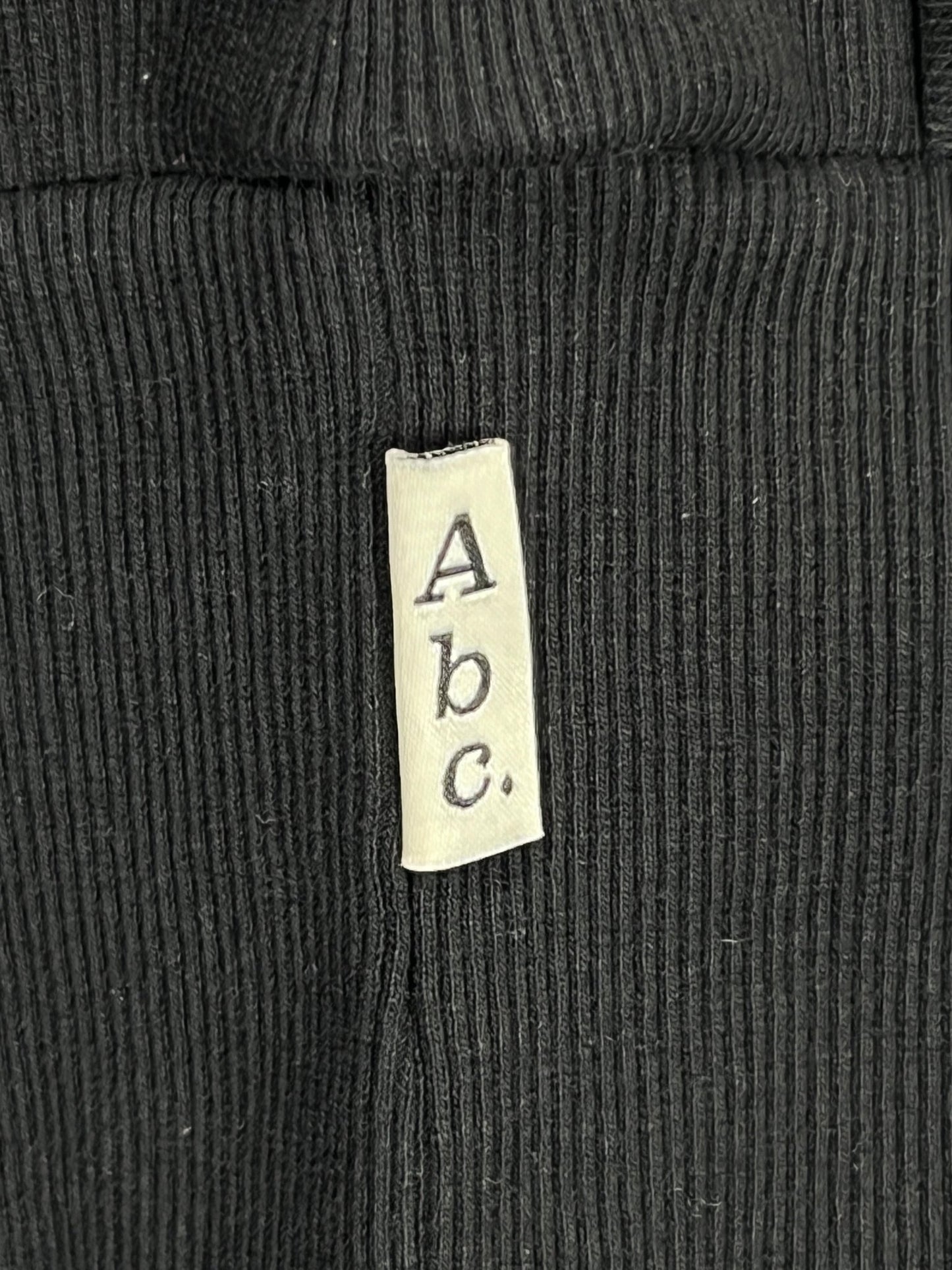 A close up of an ADVISORY BOARD CRYSTALS label on a black 100% cotton sweatshirt.