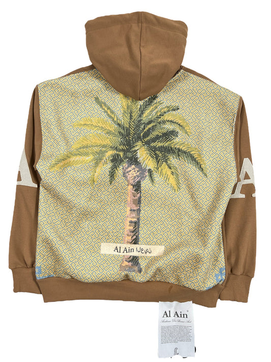 A brown AL AIN AHOX S102 PALMIER CHAMEAU hoodie with a palm tree design and "al ain" text on the front, displayed against a white background.