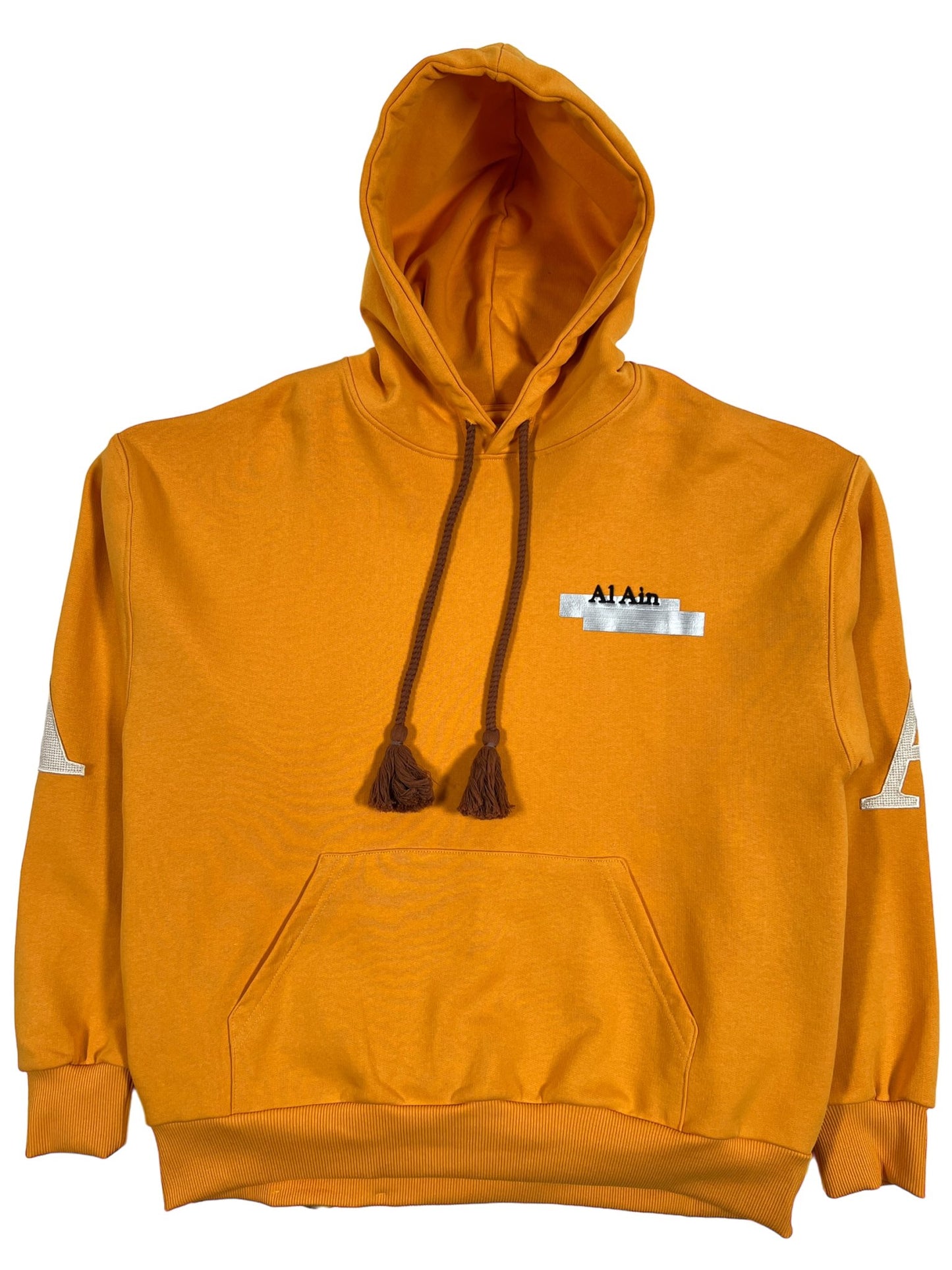 AL AIN ocre yellow hoodie with thick rope texture lace, a front pocket, and a logo patch on the left chest, displayed against a white background.