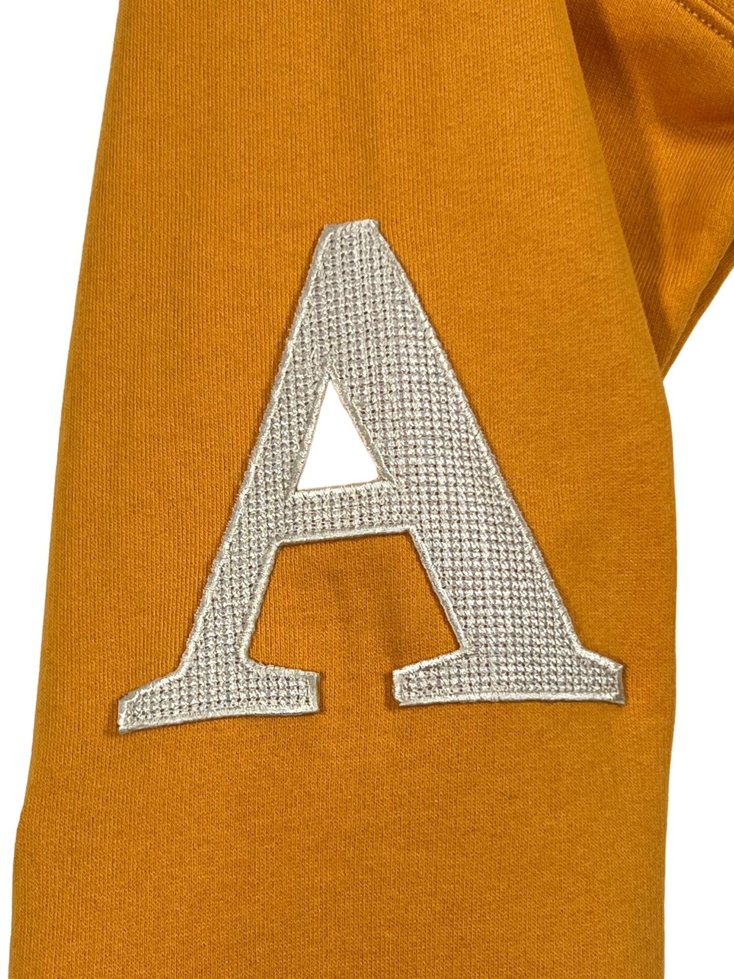 AL AIN ocre yellow hoodie with a silver letter 'a' embroidered.
