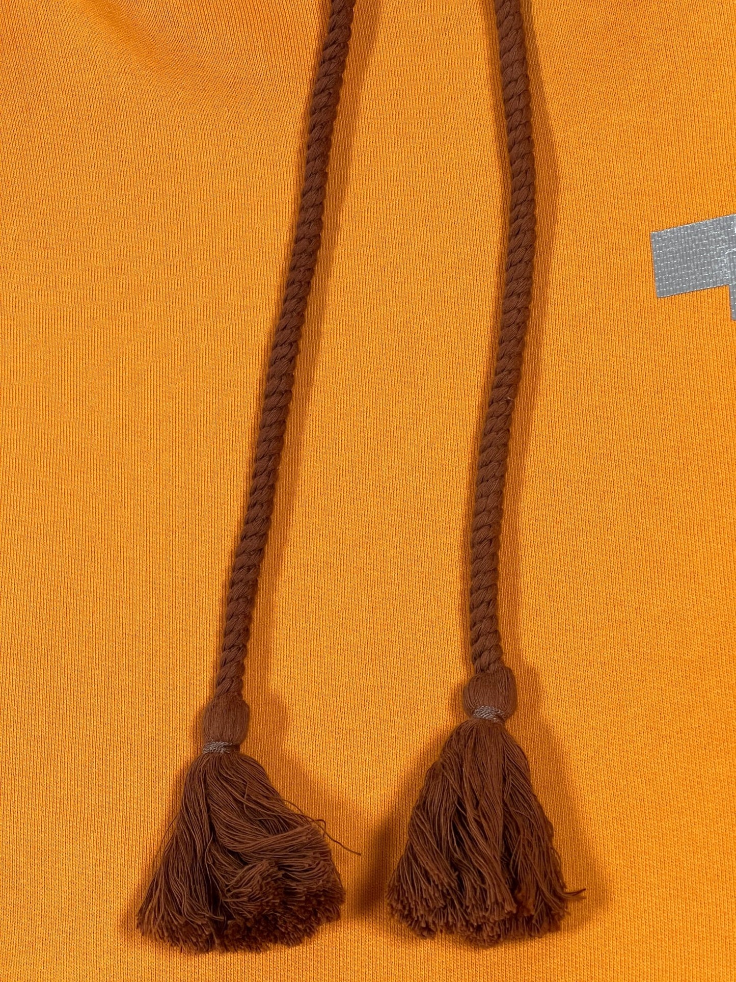 Two AL AIN tassels with a thick rope texture lace hanging against an AL AIN fabric background.