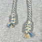 Close-up of blue and white braided drawstrings with thick rope texture lace detail on a grey AL AIN AHOX S150 YACHT LIMITED fabric background, likely part of a sweatshirt.