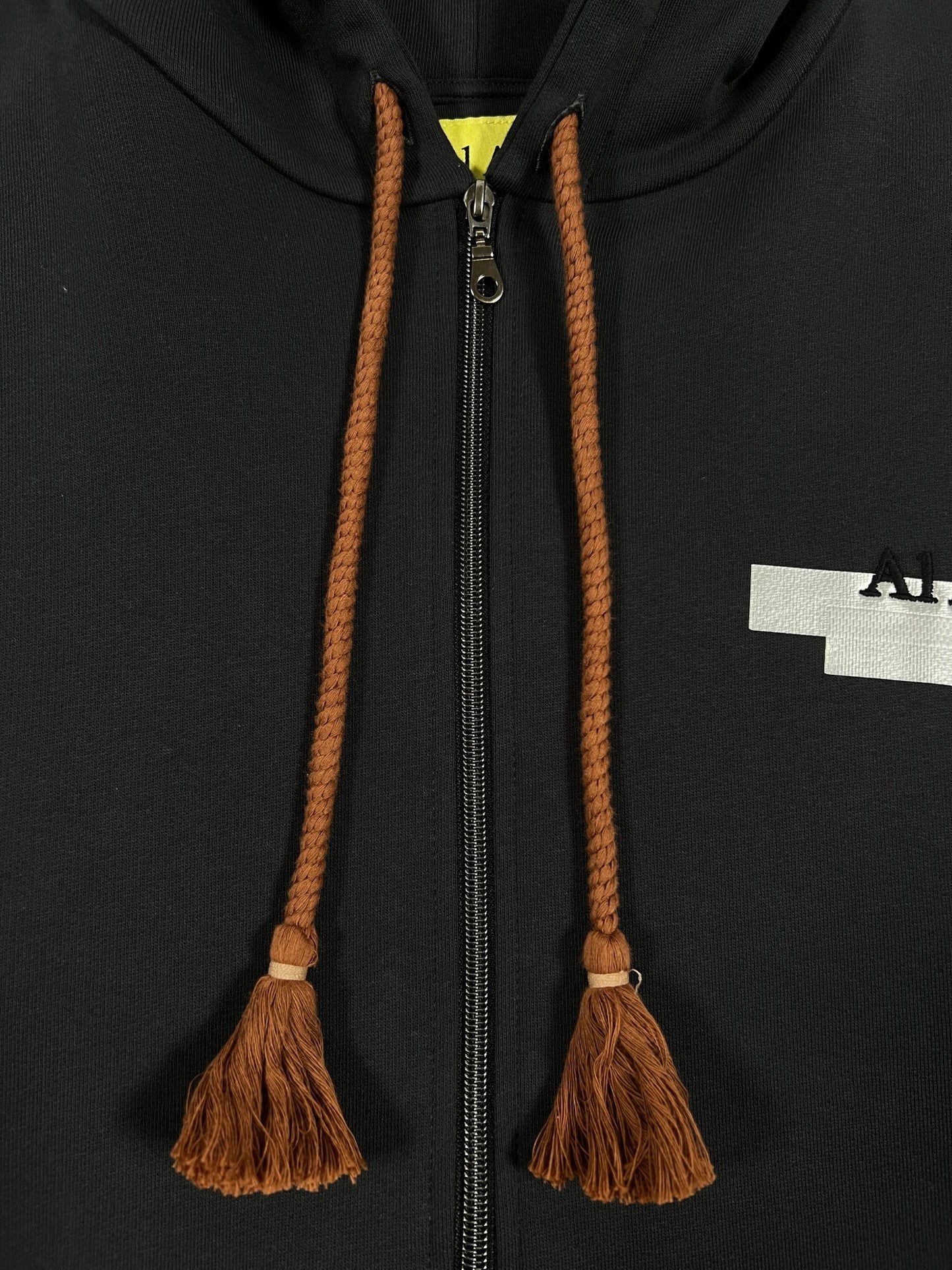 Black AL AIN AHZX S103 SECRET NOIR hoodie with a central zipper and braided drawstrings ending in tassels.