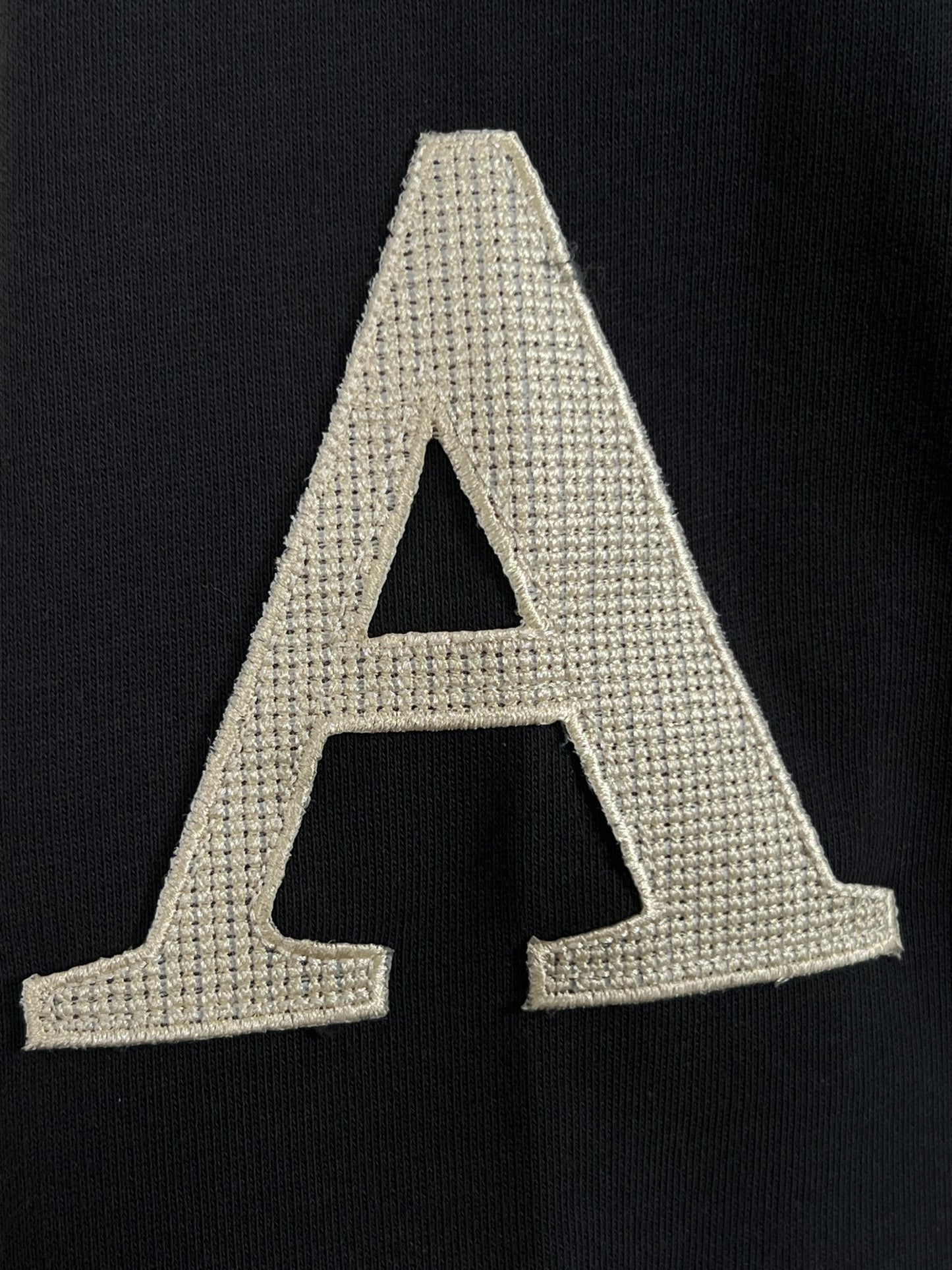 Embroidered AL AIN letter 'a' on a black 100% Cotton fabric background.