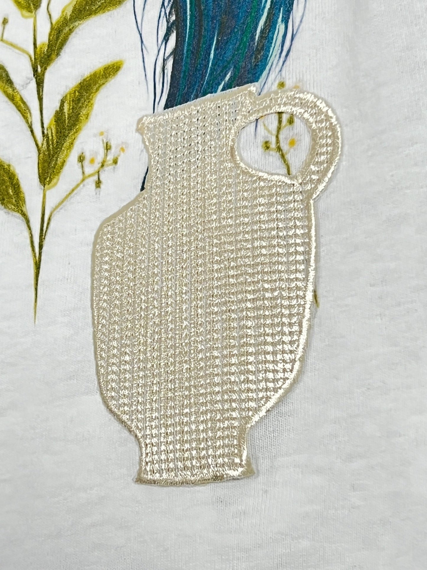 A textured, woven pitcher design in beige is displayed against a white background with large green plant illustrations, featuring the AL AIN AMHX S121 PEACOCK BLANC by AL AIN.