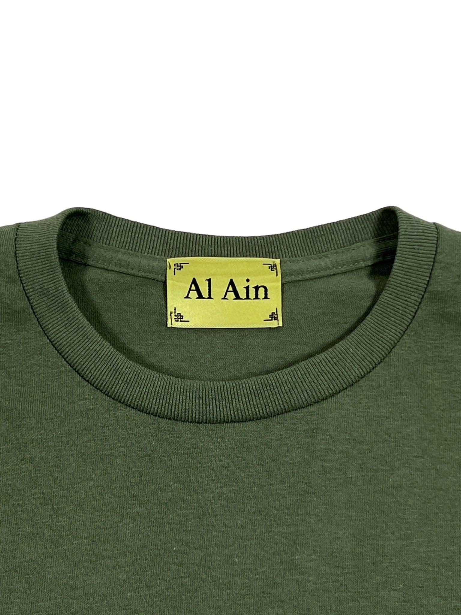 A peacock militaire t-shirt from AL AIN, showcasing an embroidered label with the words "Al Ain.