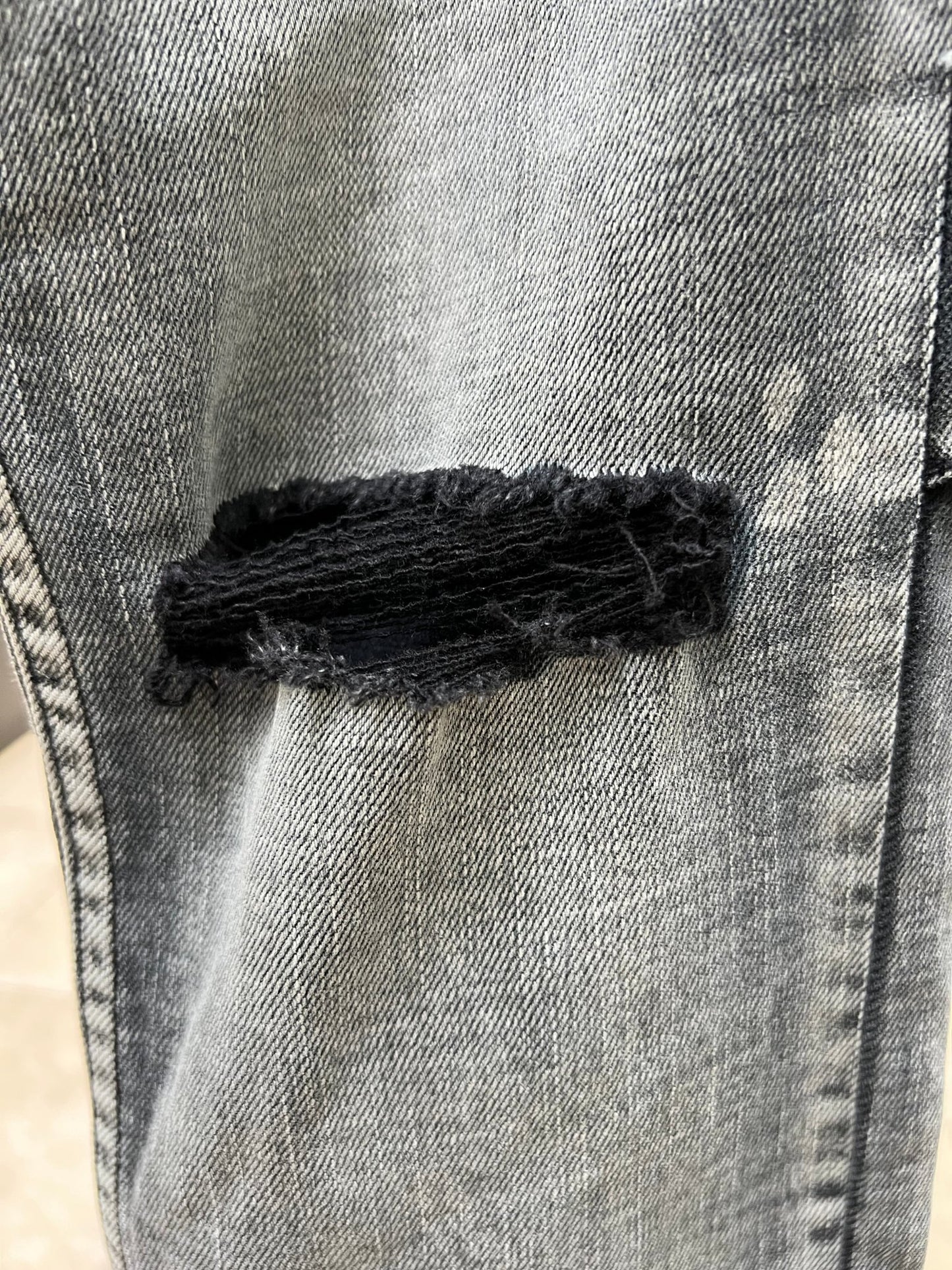 A close up of a pair of men's KSUBI CHITCH HYPNOTIZE TRASHED DENIM jeans with a hole in them.
