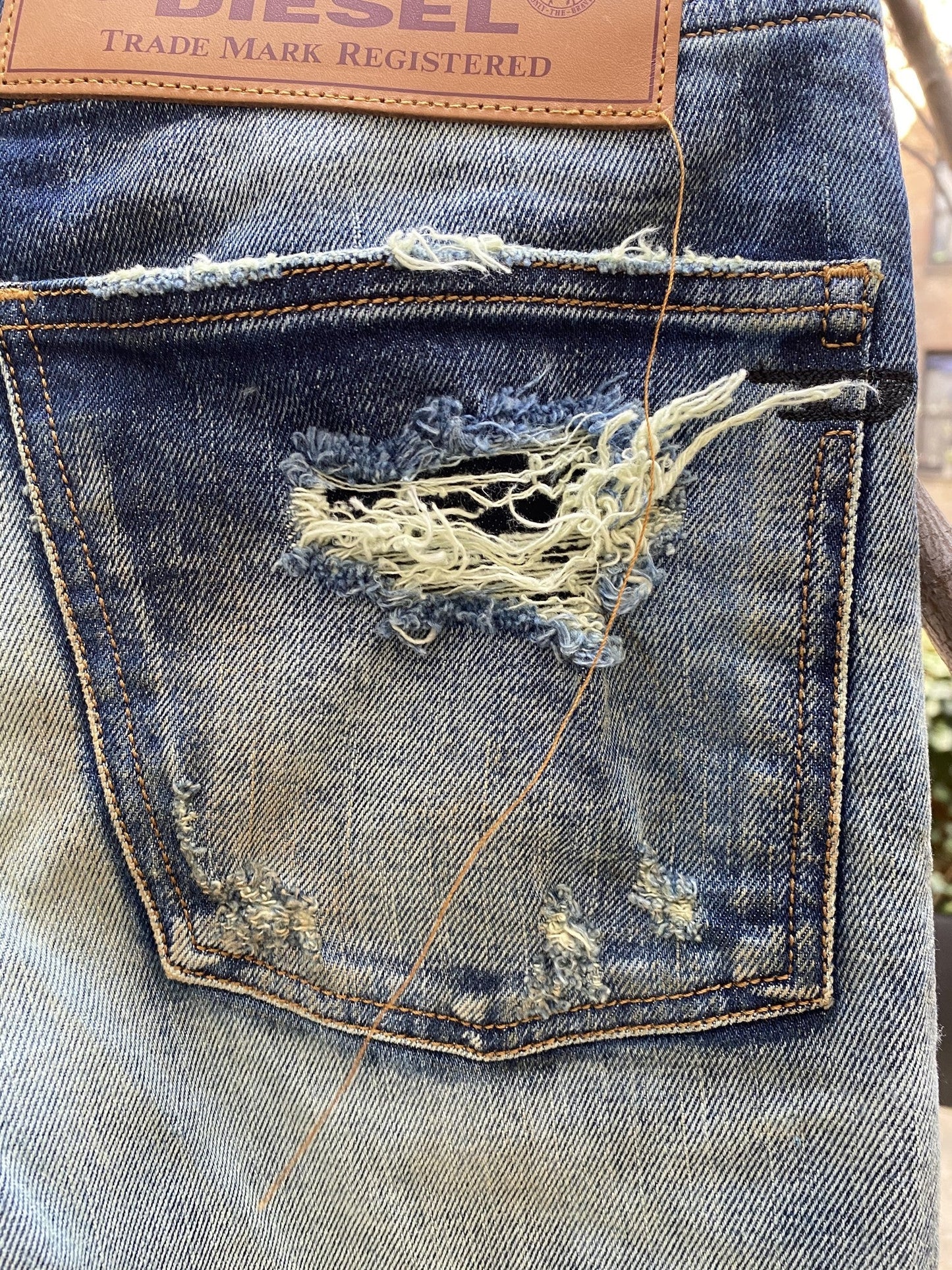 A pair of DIESEL D-KRAS-X-SP4 09VI DENIM jeans with a hole in the pocket.