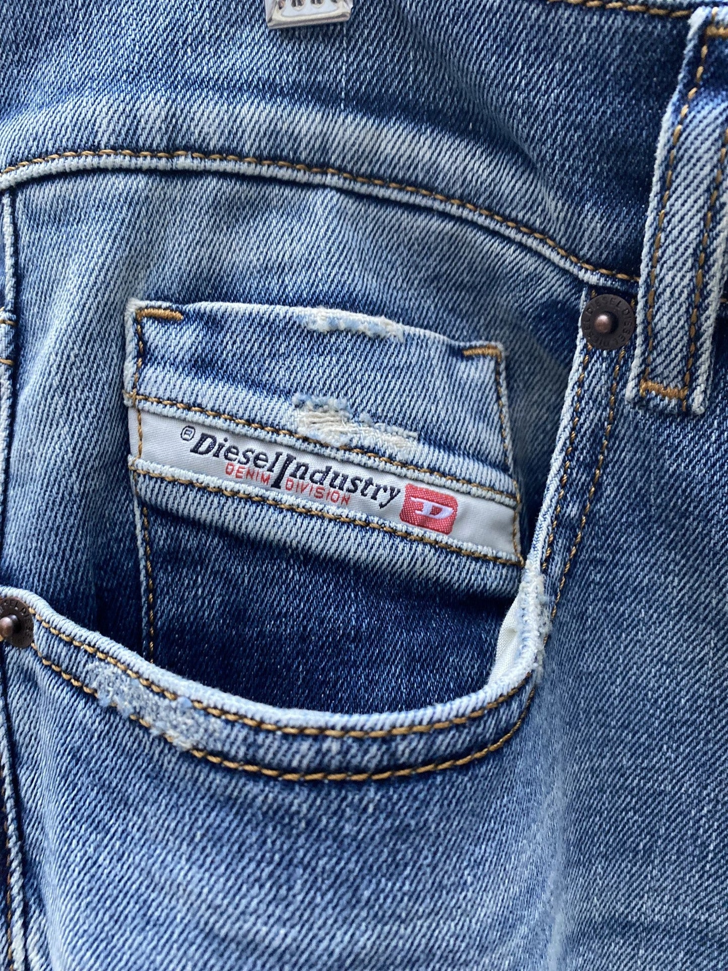 A close up of a DIESEL D-STRUKT 9C87 DENIM ripped pocket in a pair of light blue Diesel jeans.