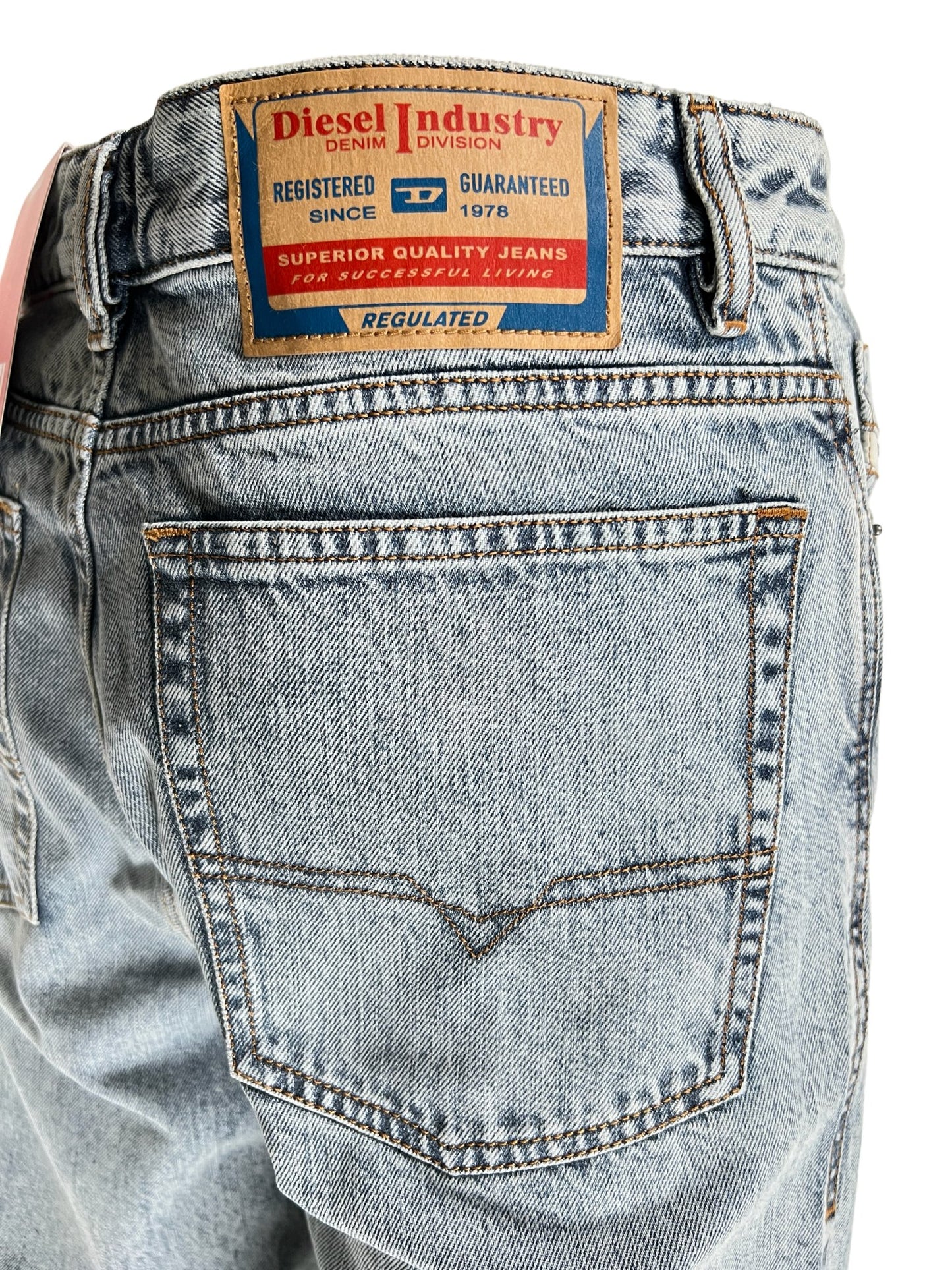 Blue light wash denim jeans with a label showing the brand DIESEL and product information on the waistband.