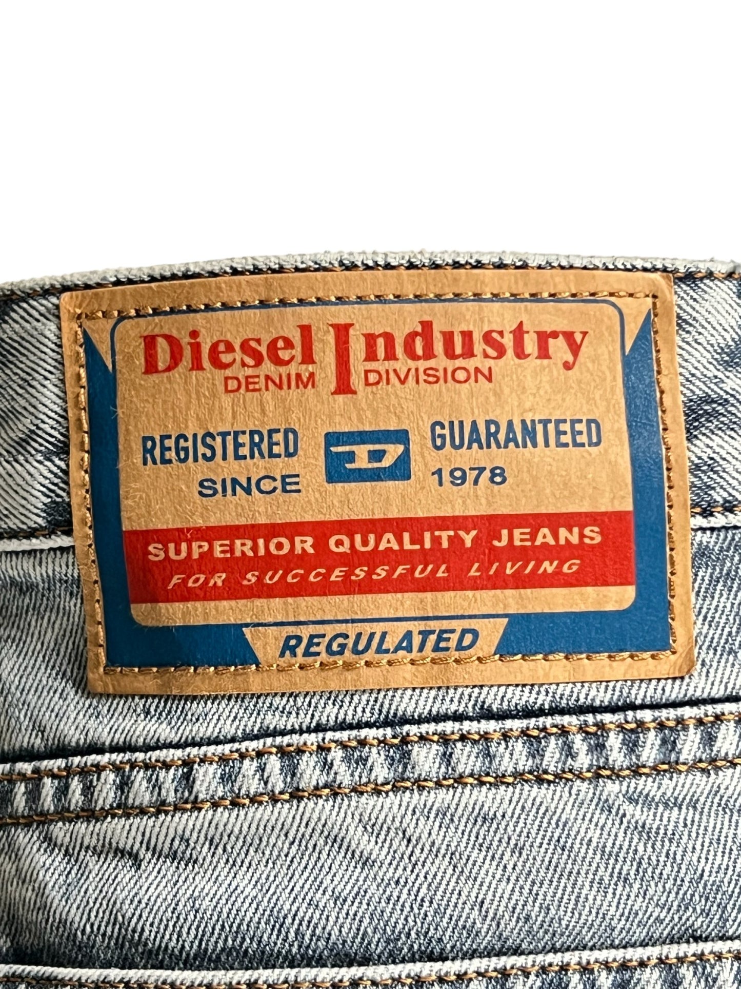 Brown leather label on light wash denim jeans displaying the Diesel 1955 D-REKIV-S1 9160 brand logo and information.