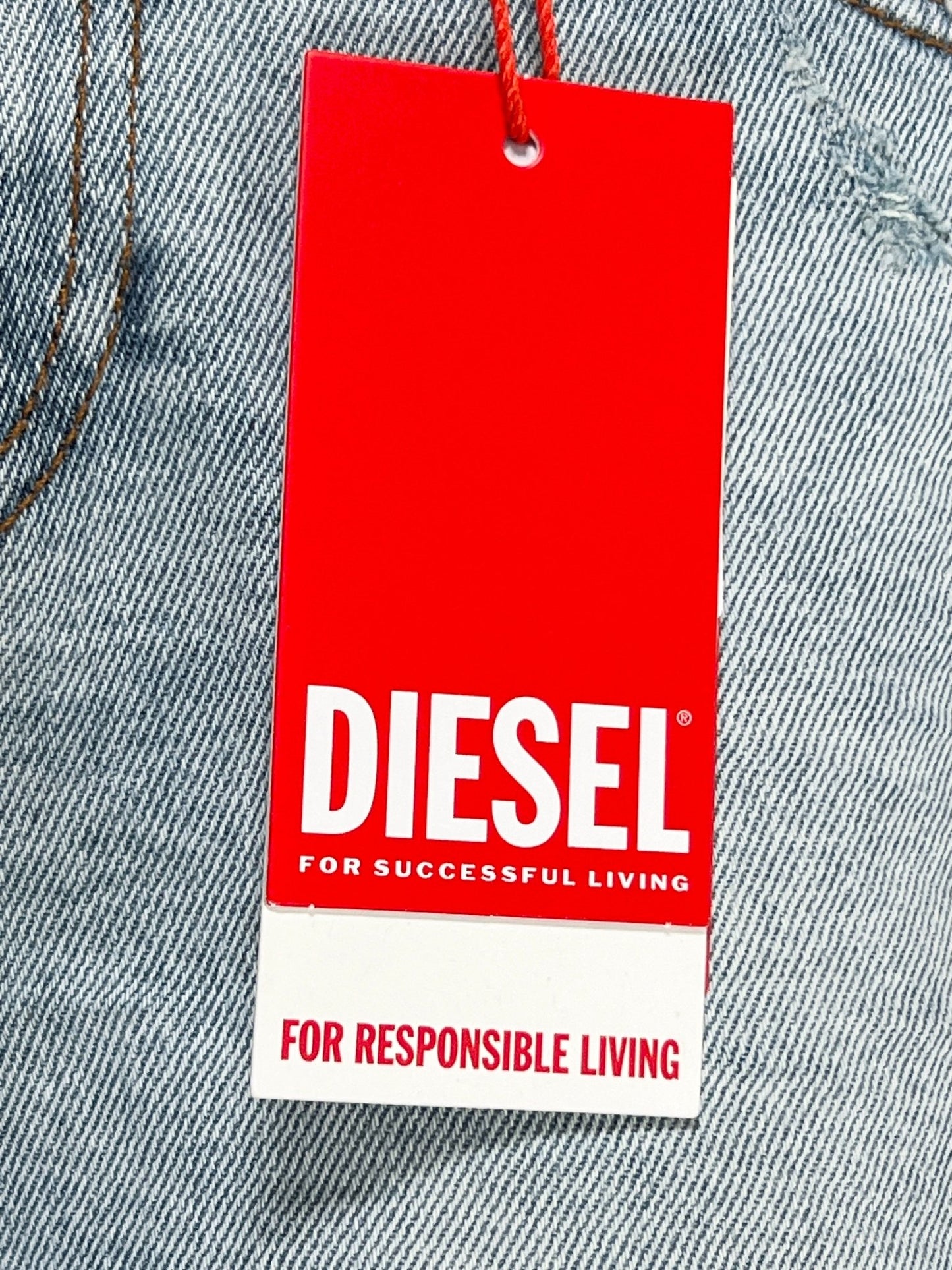 DIESEL 1979 SLEENKER 9H73 brand stretch denim clothing tag with the slogans "for successful living" and "for responsible living" on a gray fabric background.