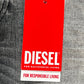 The Diesel 1979 Sleenker 9H74 skinny jeans, made from organic cotton stretch denim, feature a red tag with "DIESEL" and the phrases "For Successful Living" and "For Responsible Living," set against a gray fabric backdrop.
