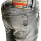 Close-up of Diesel 1979 Sleenker 9H74 light gray skinny jeans made from stretch denim, with a DIESEL Industry label on the back waistband.