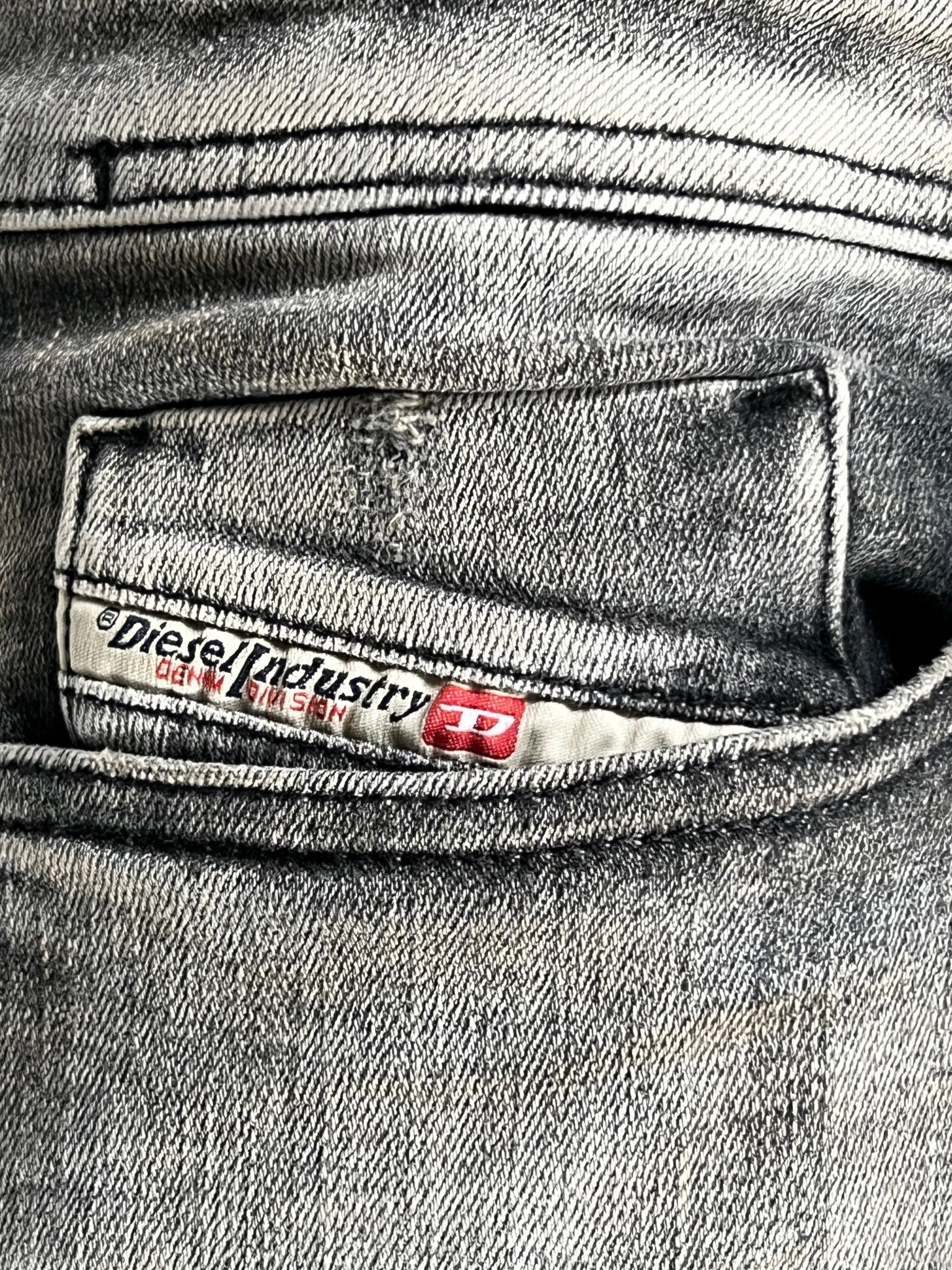 Close-up of a gray pocket from the Diesel 1979 Sleenker 9H74 stretch denim jeans, featuring a label with "Diesel Industry" in red and black text.