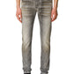 A person wearing Diesel 1979 Sleenker 9H74 skinny gray denim jeans by DIESEL and black sneakers stands against a plain white background.