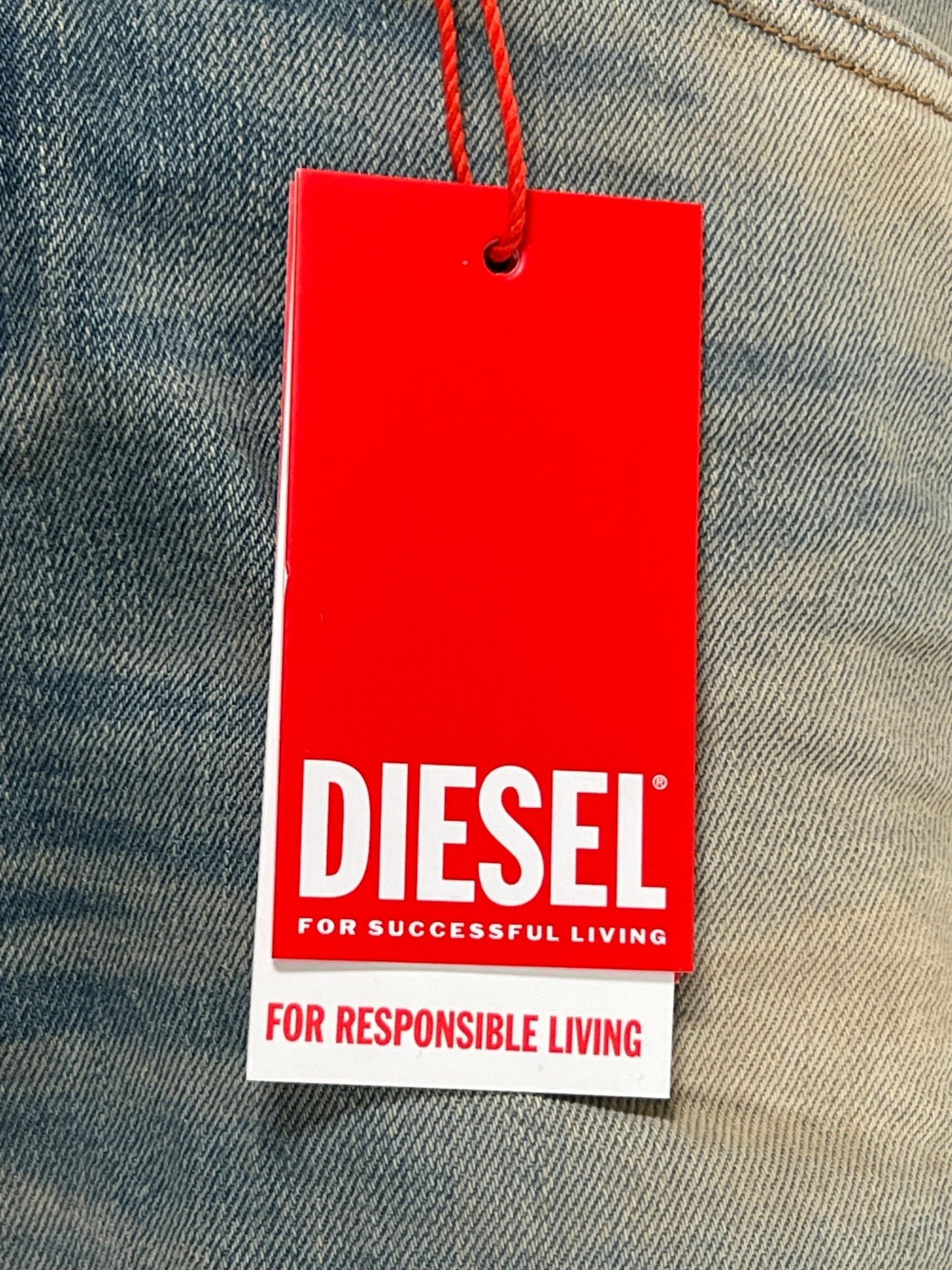 A medium blue wash DIESEL bootcut jeans clothing tag with the slogan "for successful living" followed by "for responsible living.