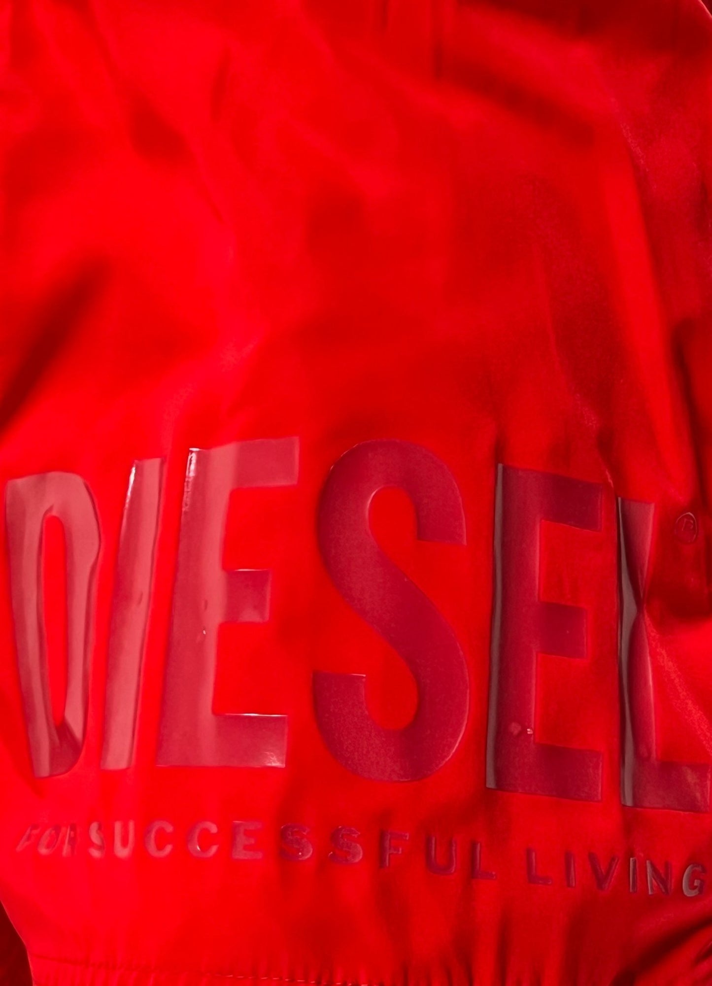 Close-up of men's swimming shorts with a glossy logo print on the red DIESEL BMBX-MARIO-34 SHORT RED.