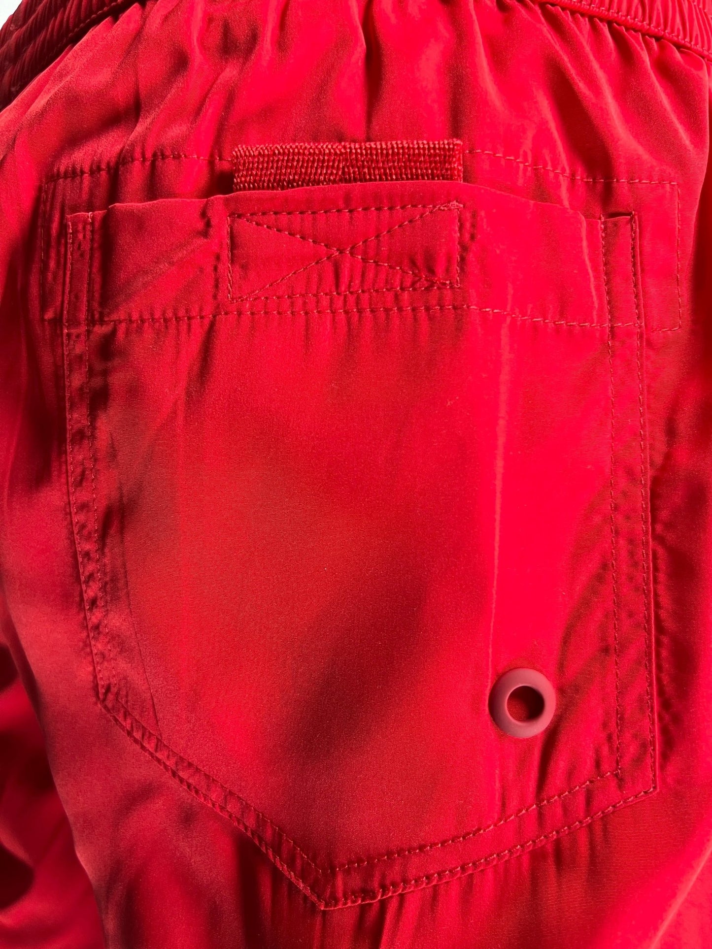 Close-up of a red fabric pocket with visible stitching and a buttonhole on Diesel BMBX-Mario-34 Short Red swimming shorts.
