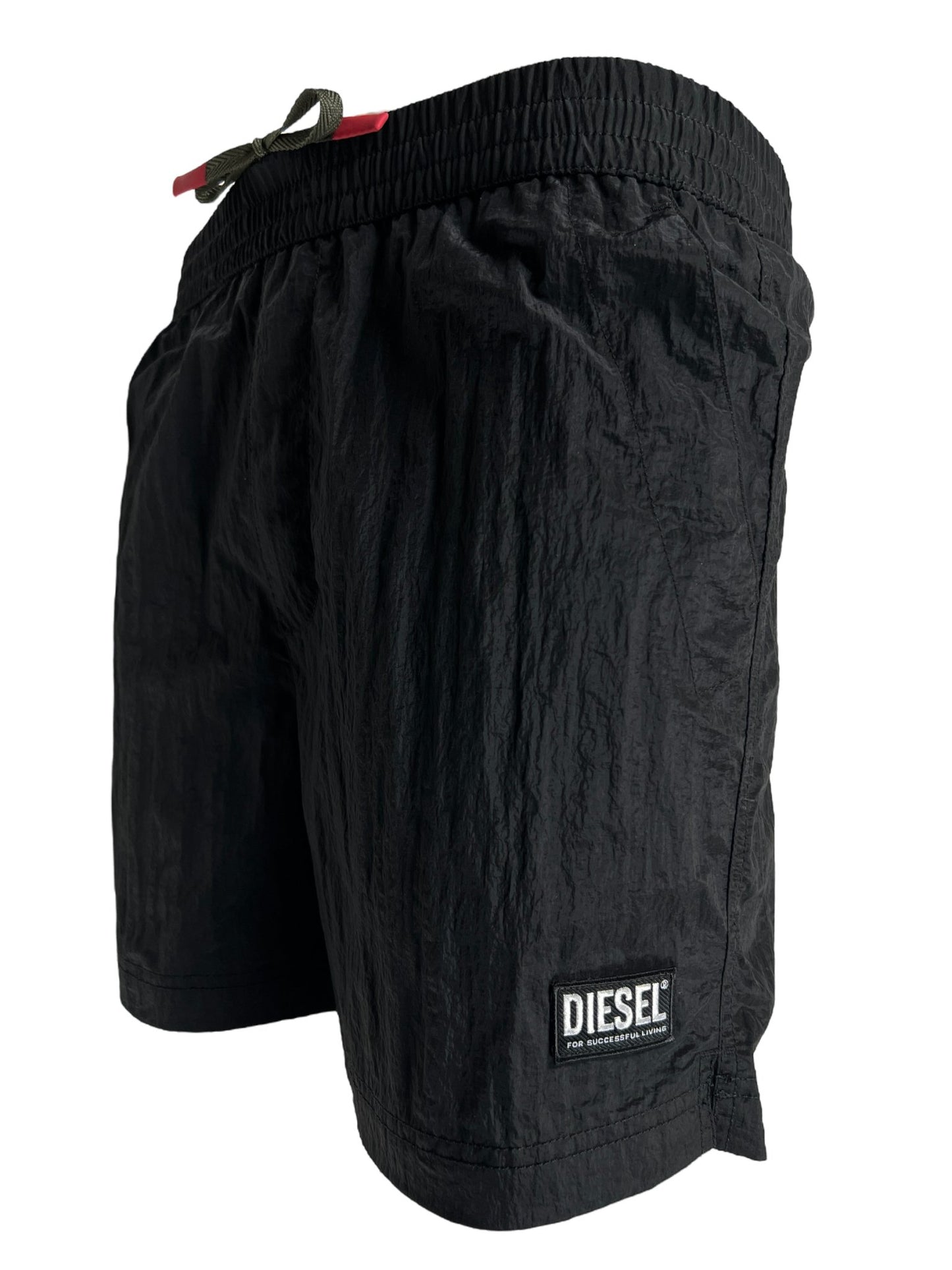 Black DIESEL men's board shorts made from recycled fabric, with elasticated waist and logo patch on the right side, isolated on white background.