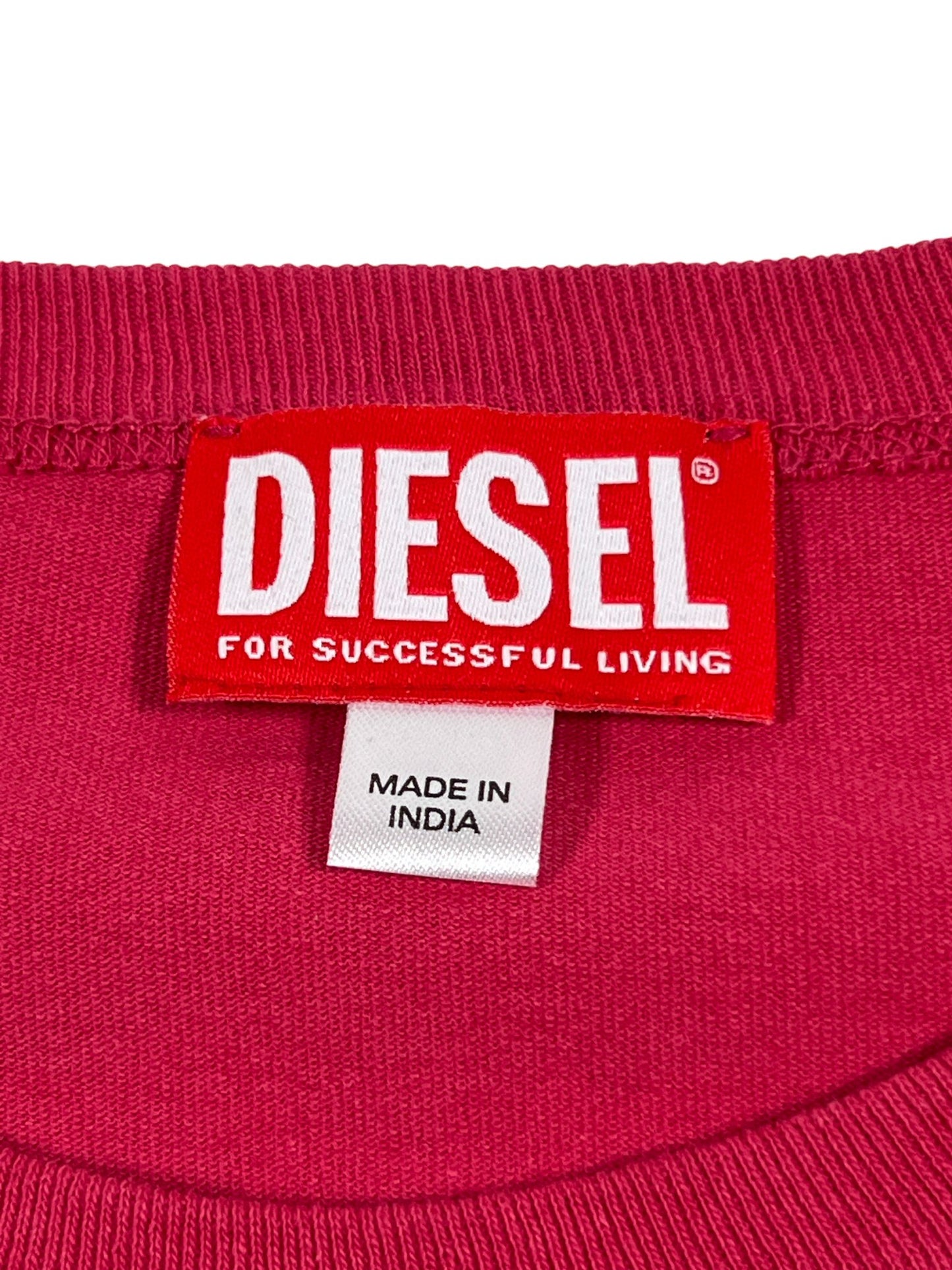 Close-up of a DIESEL T-RUST T-SHIRT BABY PINK brand label on pink 100% Cotton fabric with a secondary 'made in India' tag.