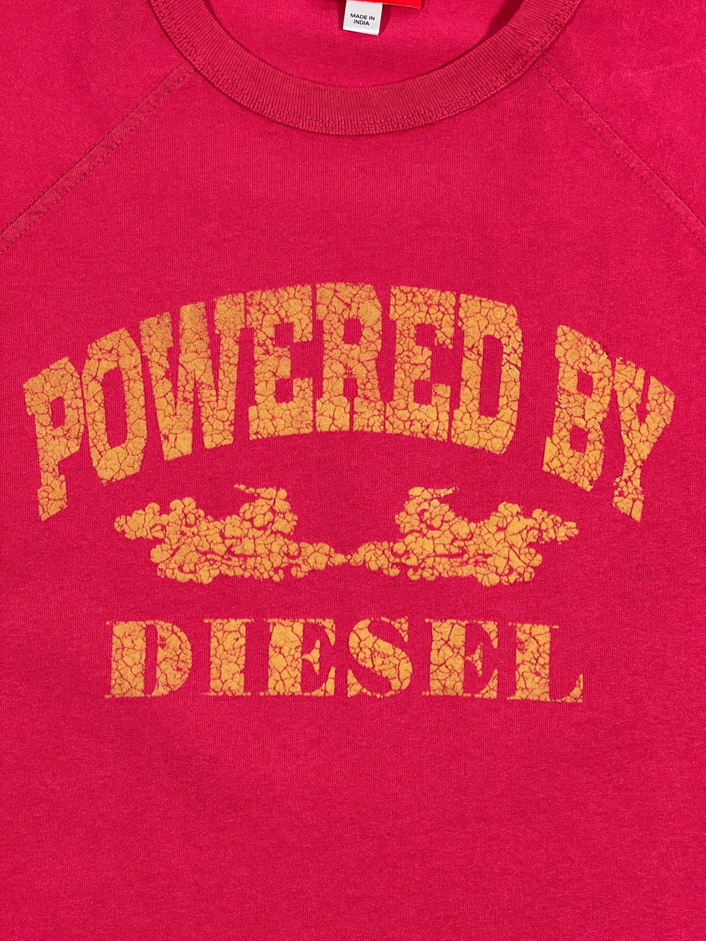 Pink DIESEL T-RUST t-shirt with the phrase "powered by diesel" printed in yellow text with a distressed look.
