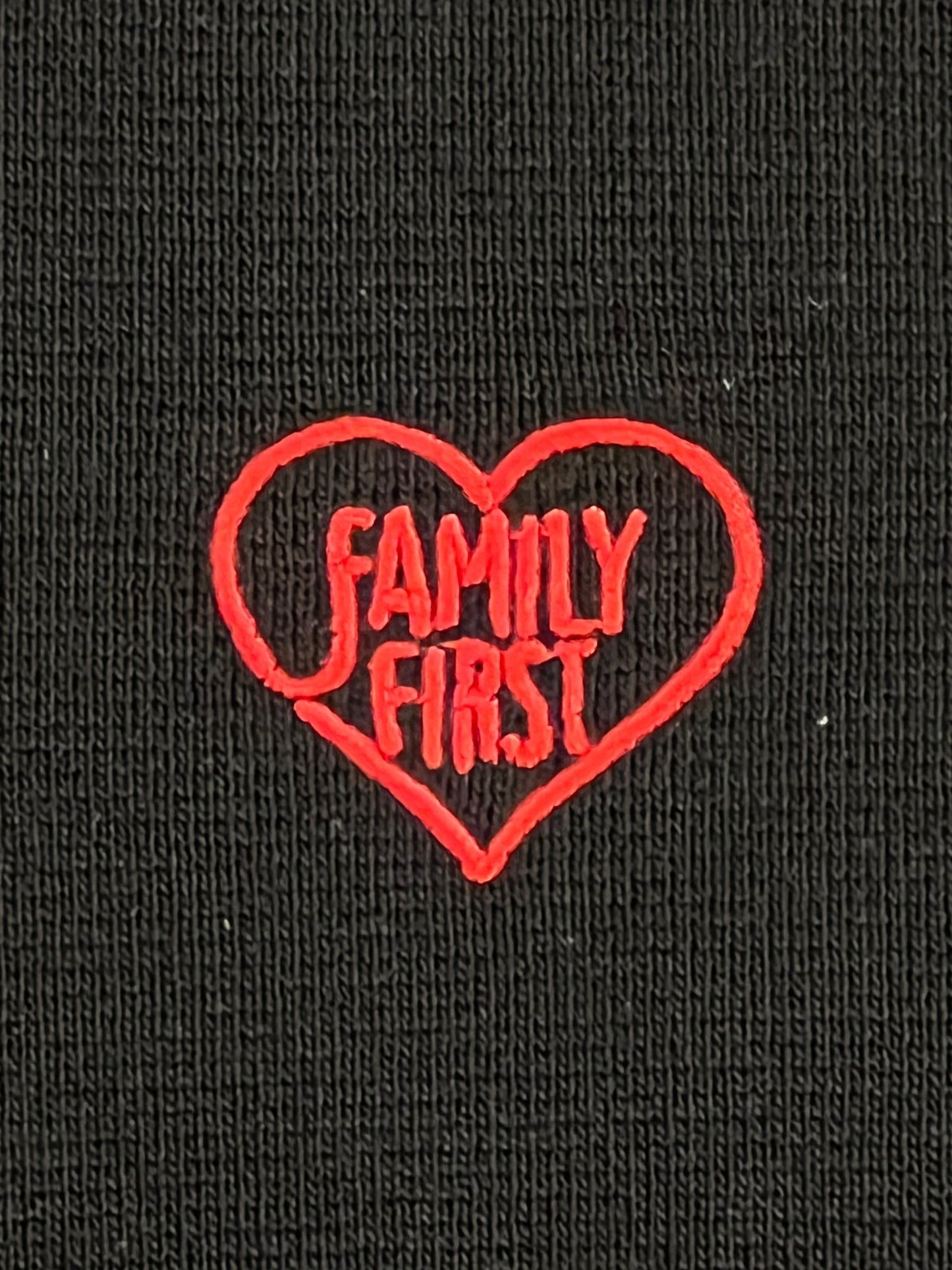 A black hoodie with an embroidered heart logo on it that says FAMILY FIRST – FAMILY FIRST SWS2401 HOODIE SWEATER BK.
