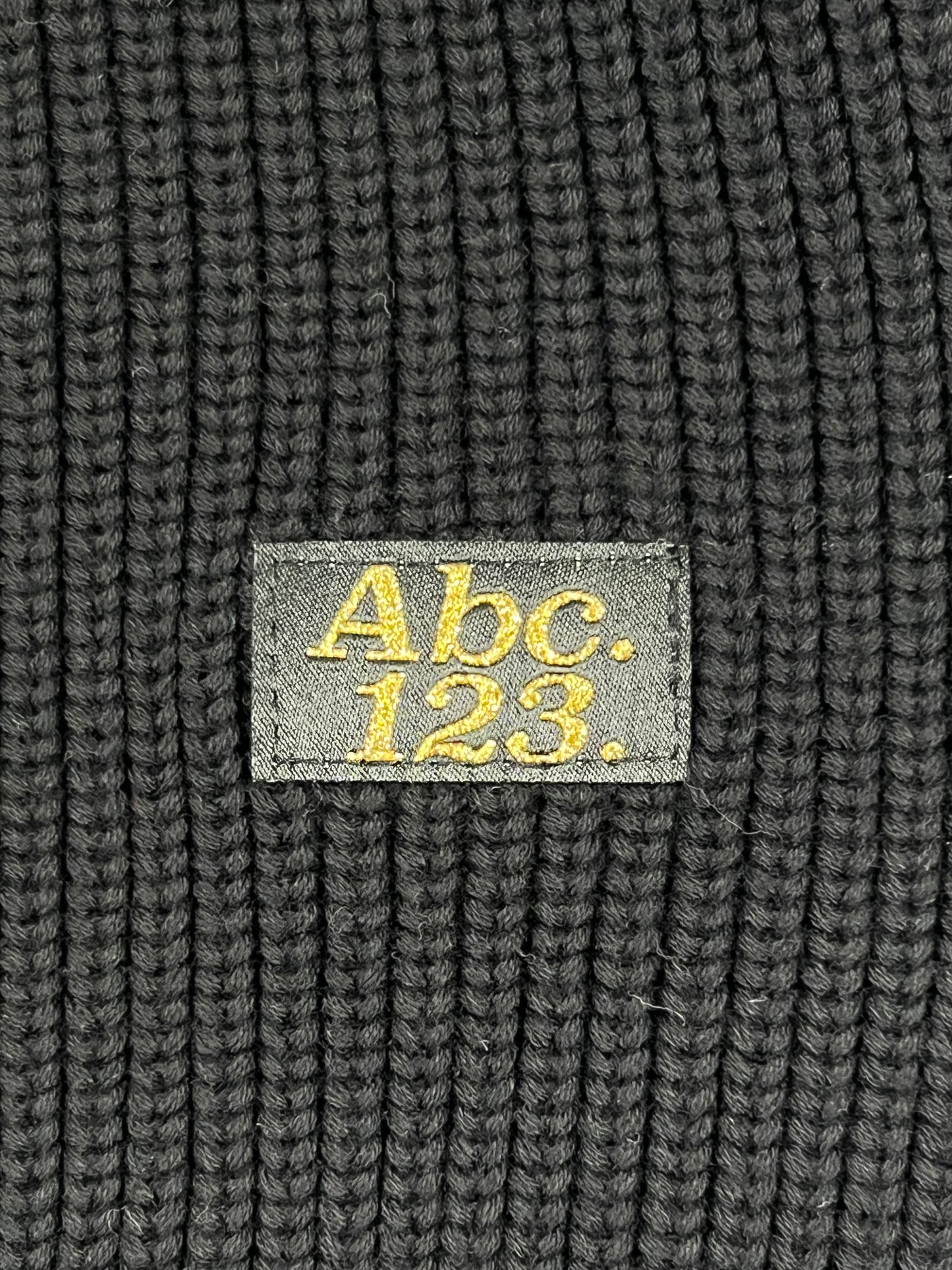A ribbed crewneck in anthracite black with an embroidered logo reading "abc123" on it by ADVISORY BOARD CRYSTALS.