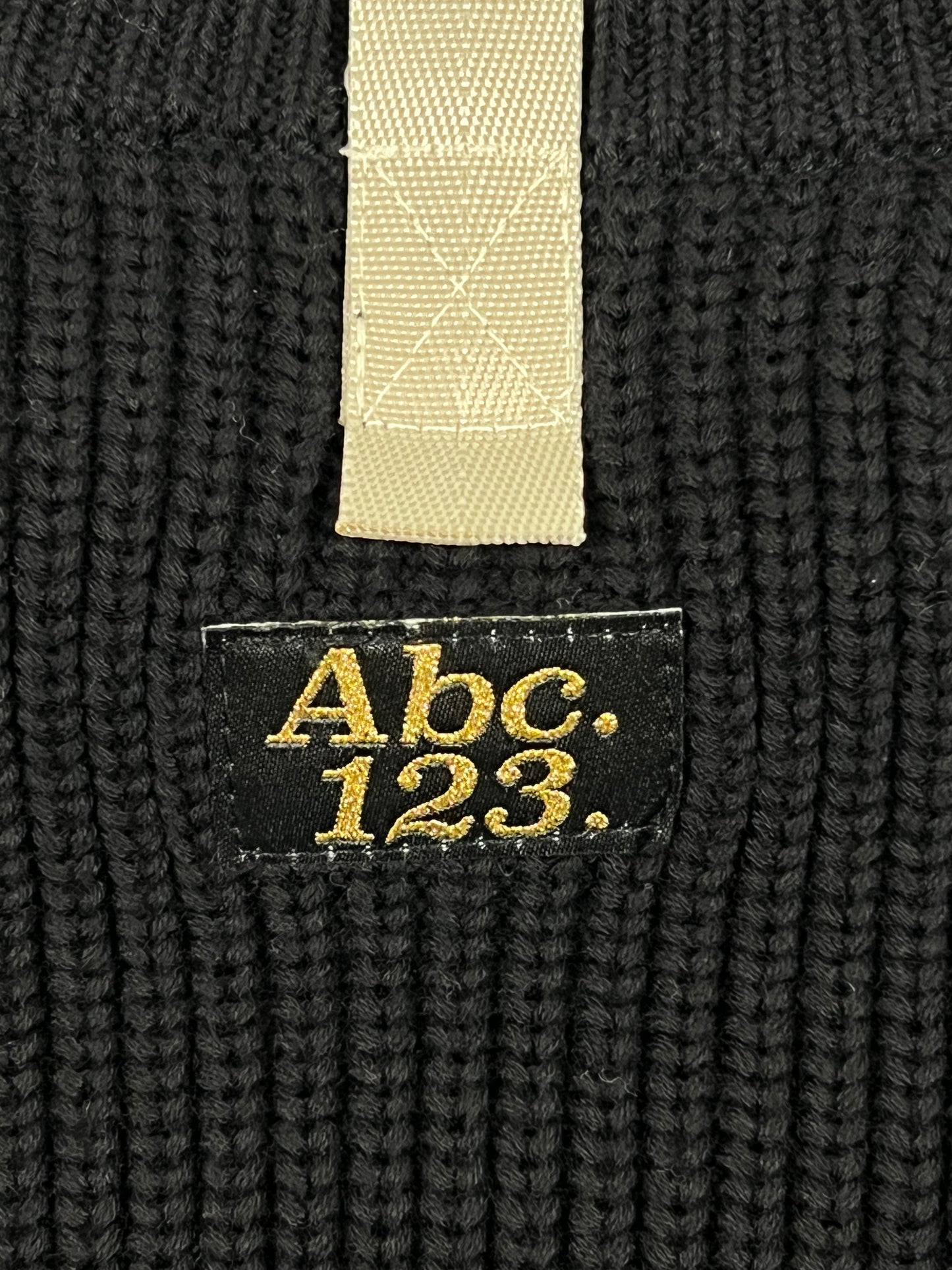 A ADVISORY BOARD CRYSTALS RIBBED CREWNECK ANTHRACITE BLACK with a gold embroidered logo on it.