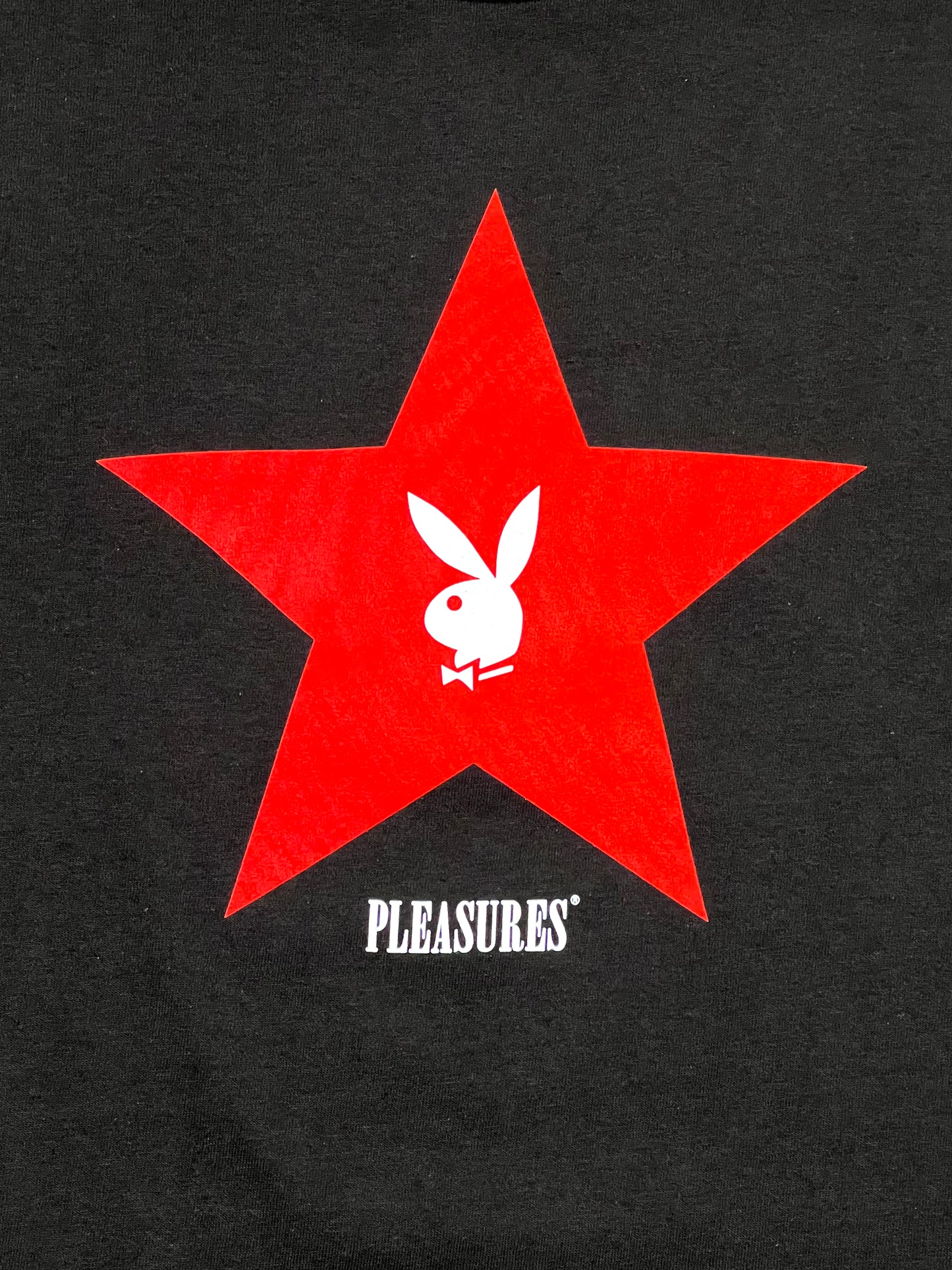 A PLEASURES black sweatshirt with a red star on it.