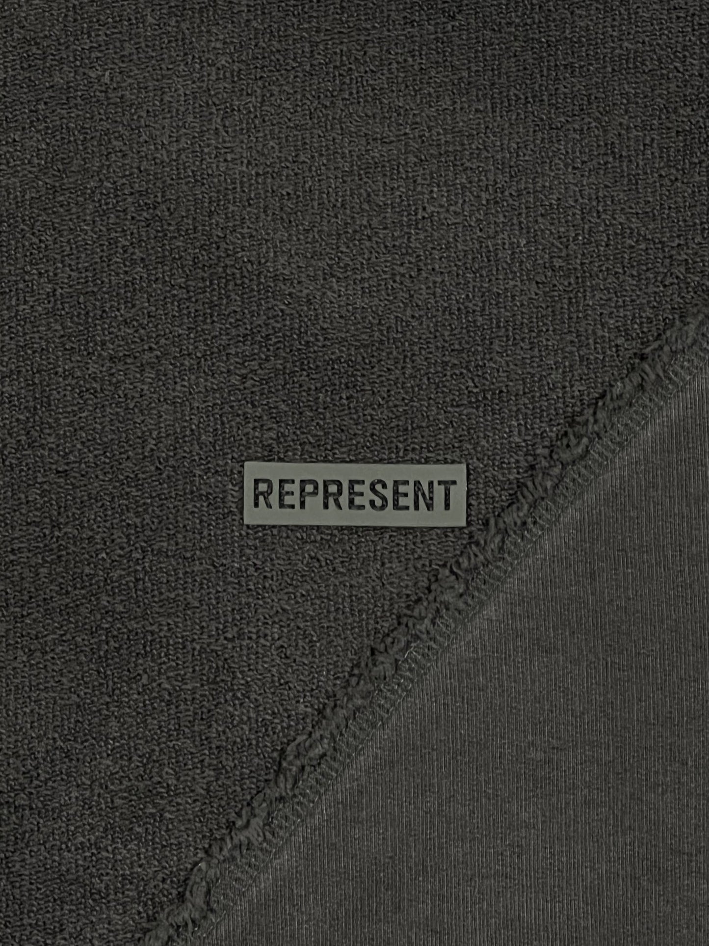 A close up of a black cotton sweatshirt with the word "REPRESENT" on it.