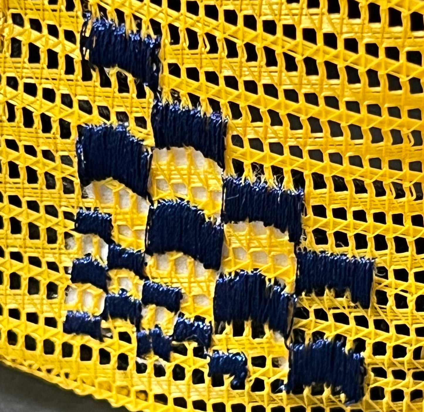 A close up of a yellow and blue fabric with embroidered RHUDE branding.