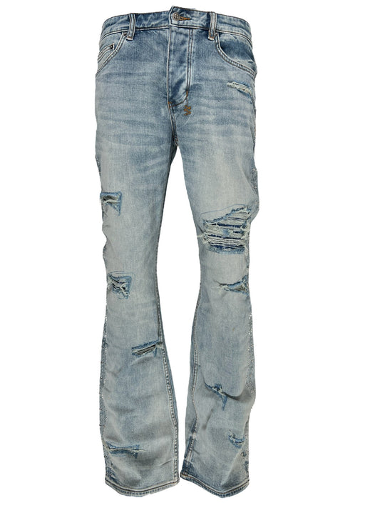 Distressed bootcut jeans with rips and faded patterns on a white background in the KSUBI BRONKO DYANAMITE METAL DENIM.