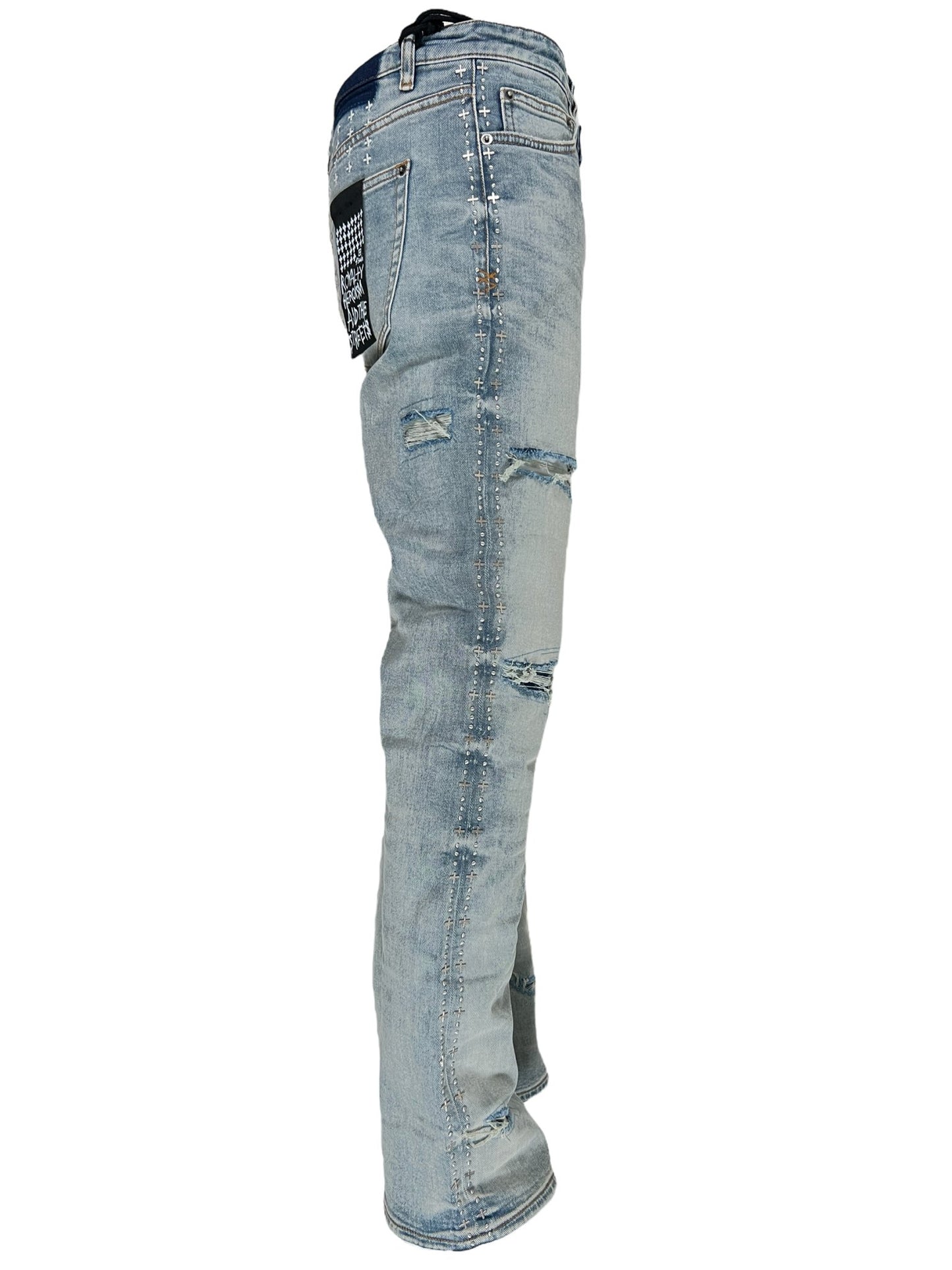 Side view of a pair of distressed Ksubi KSUBI BRONKO DYANAMITE METAL DENIM blue jeans with patchwork details.