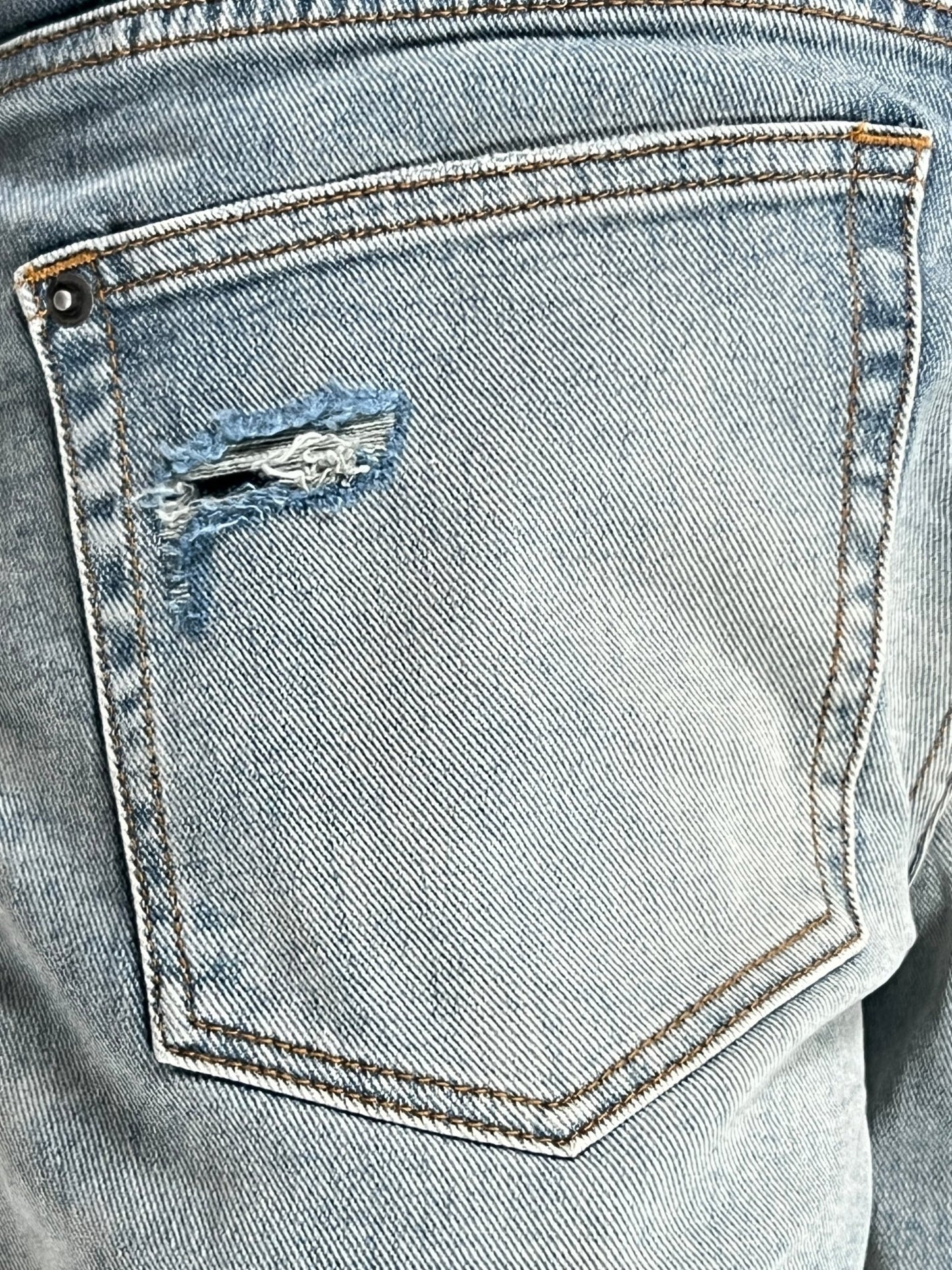 Close-up of a worn KSUBI BRONKO DYANAMITE METAL DENIM pocket with fraying edges.