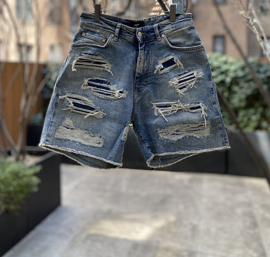 A pair of Represent M07062 Shredded Denim Shorts in Blue Cream hanging on a hanger.