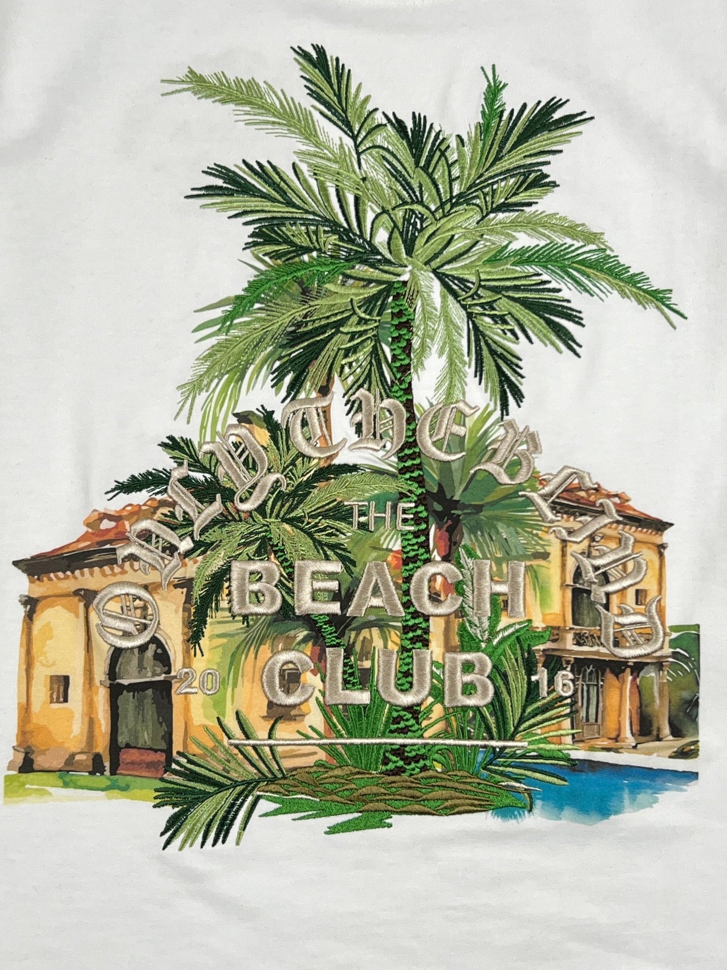 A white t-shirt with an image of a ONLY THE BLIND desert palm tree and a house.