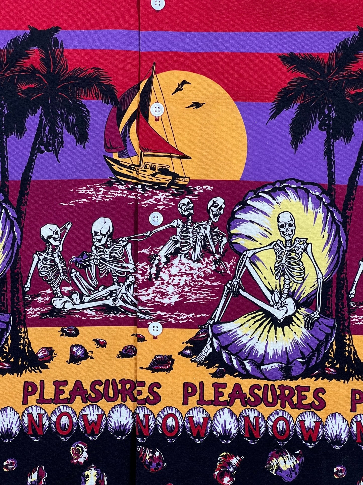 A Pleasures Beach Button Down Burgundy Hawaiian short sleeve shirt with skeletons and palm trees.