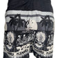 A black PLEASURES BEACH SHORT BLACK with palm trees and skeletons on it.