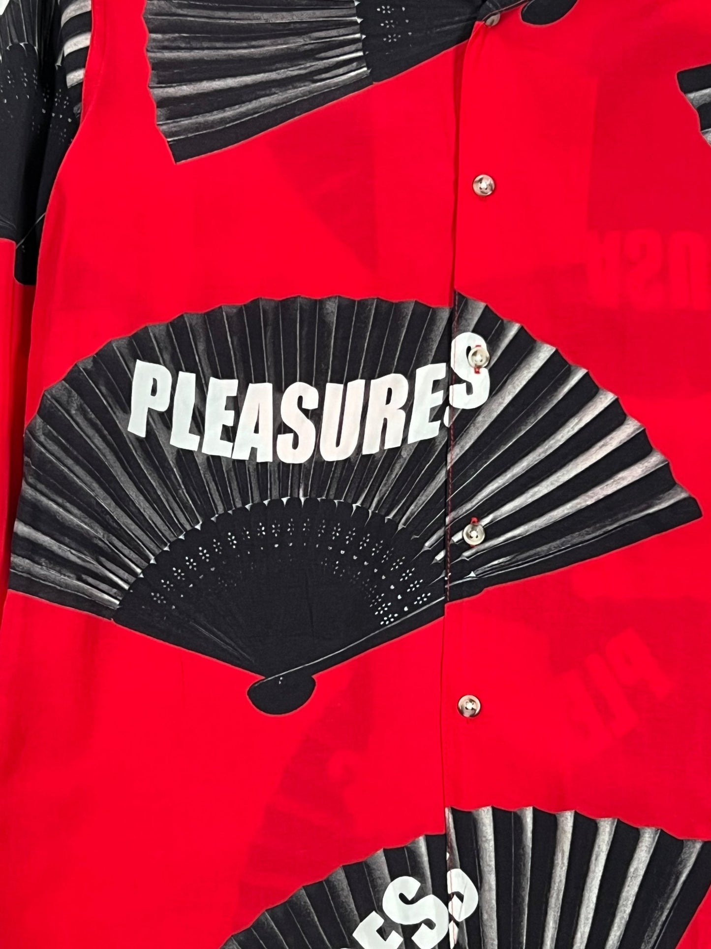 The PLEASURES FANS long sleeve button-down shirt in red and black offers unparalleled comfort.